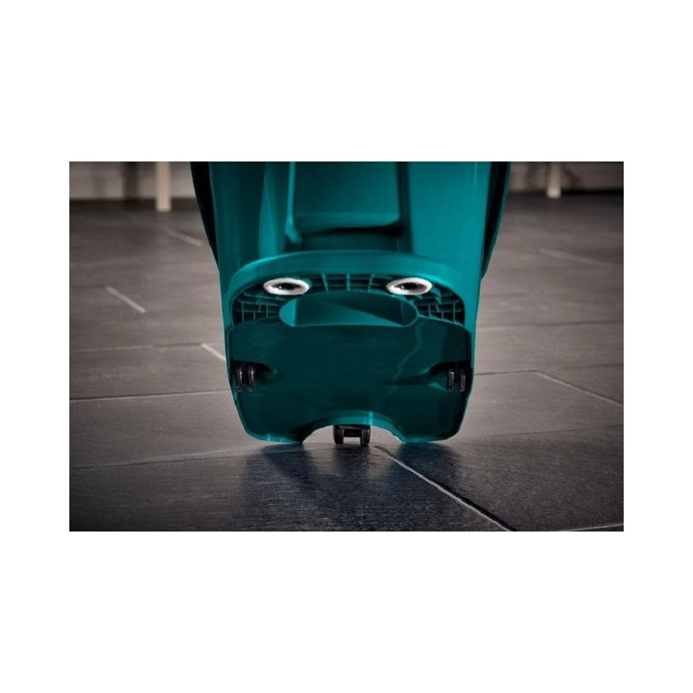 Zbliżenie na spód turkusowego urządzenia z kołami na ciemnej podłodze.