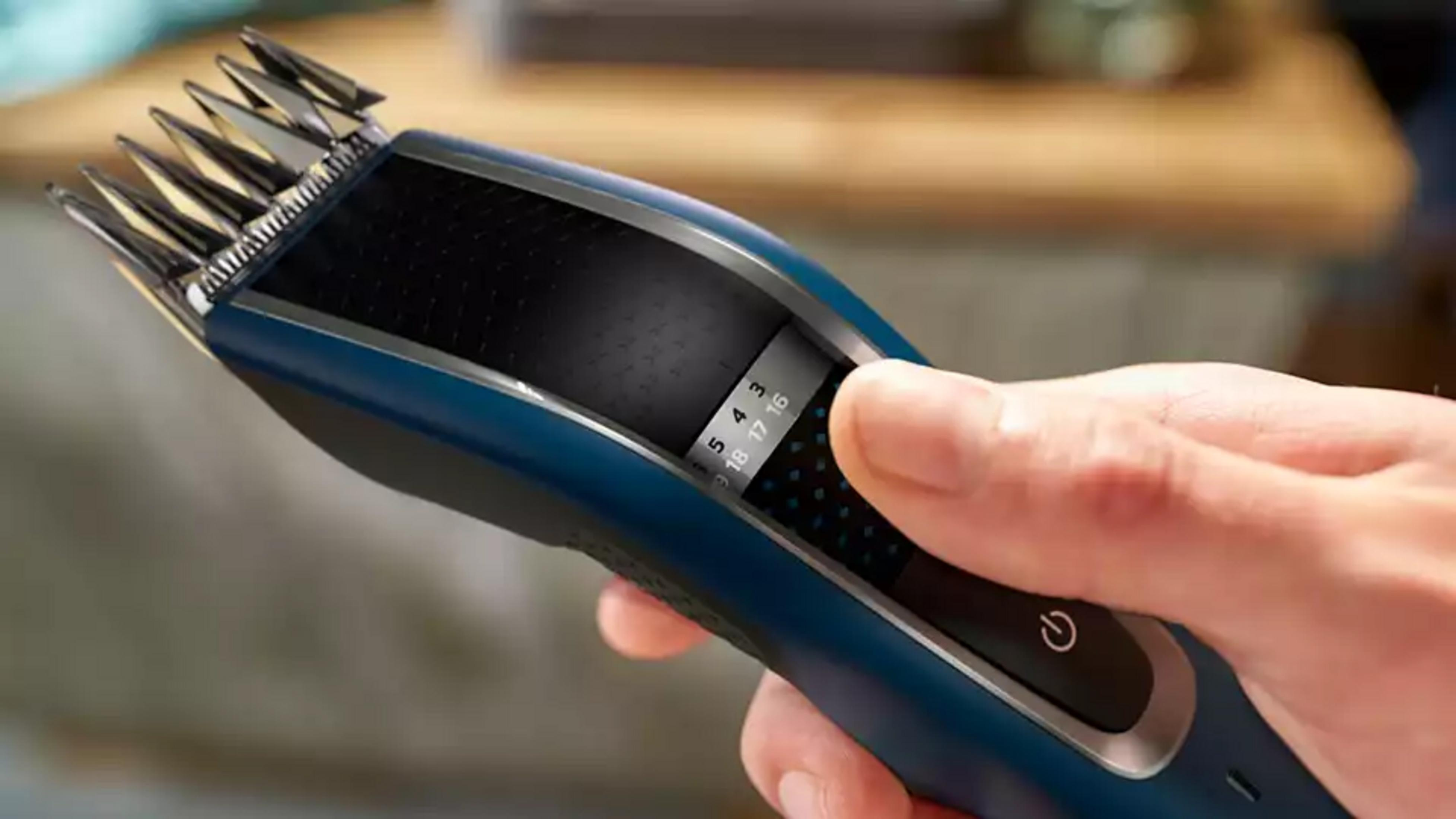 Blaue Haarschneidemaschine mit silbernen Klingen, die von einer Hand bedient wird.