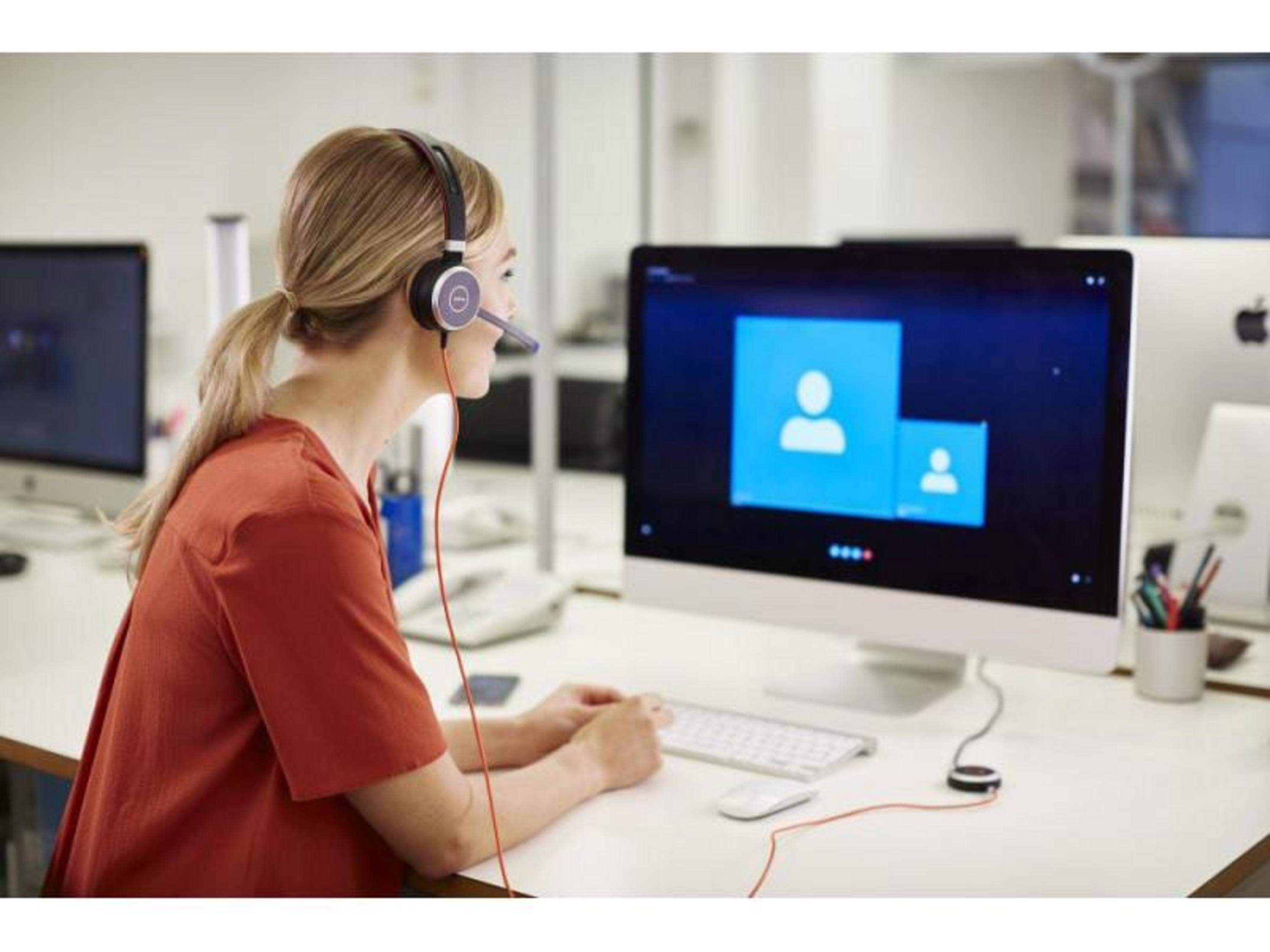 Femme avec casque au bureau en appel vidéo.
