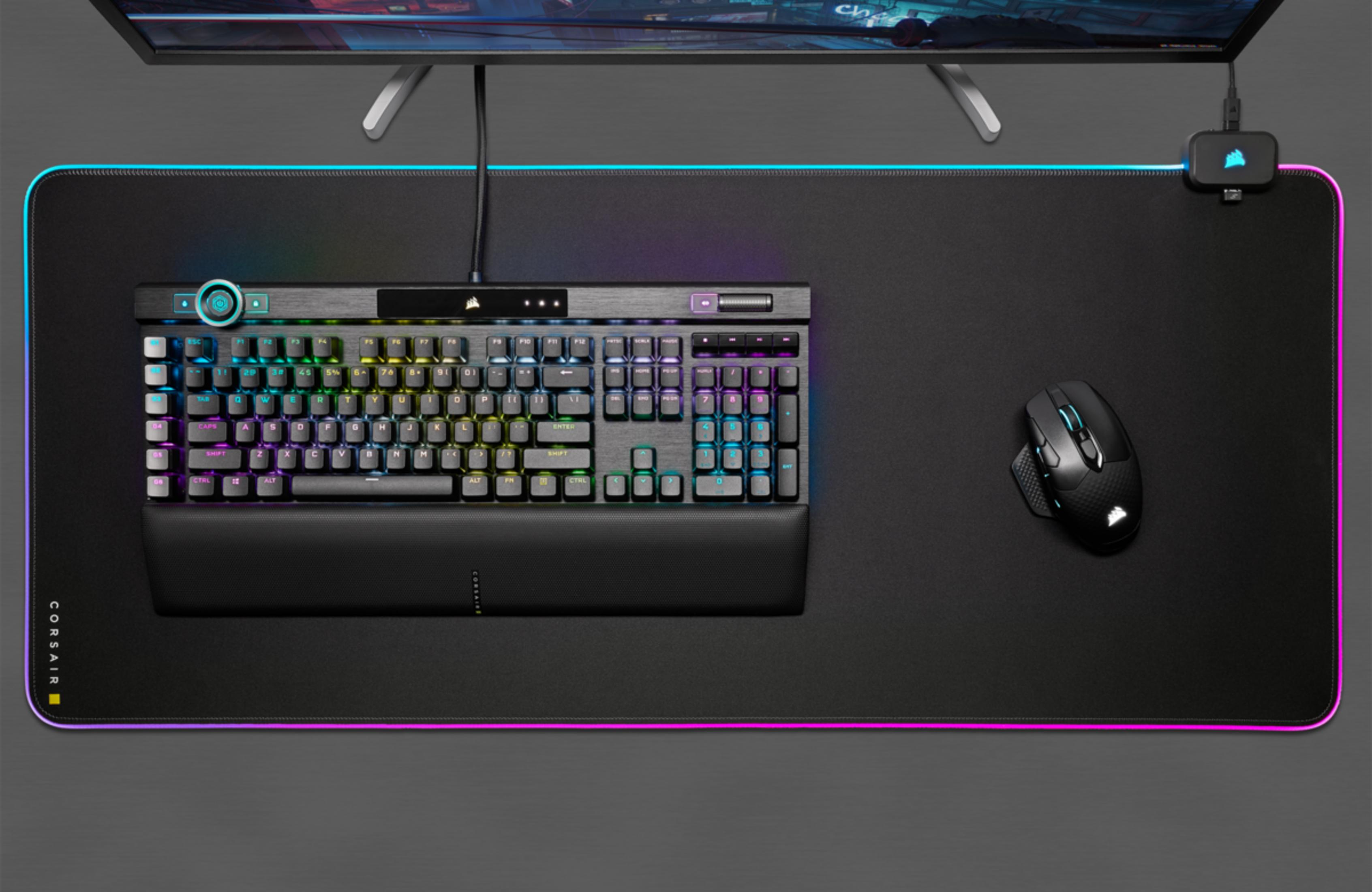 Czarna klawiatura i mysz na macie z podświetleniem RGB przed monitorem.