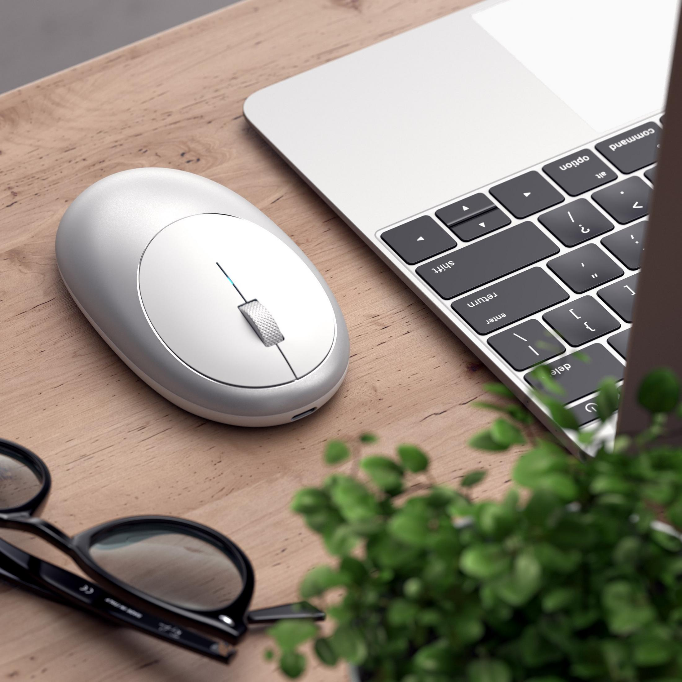 Ein weißes Maus, Laptop-Tastatur, Brille und Pflanzen auf einem Holztisch.