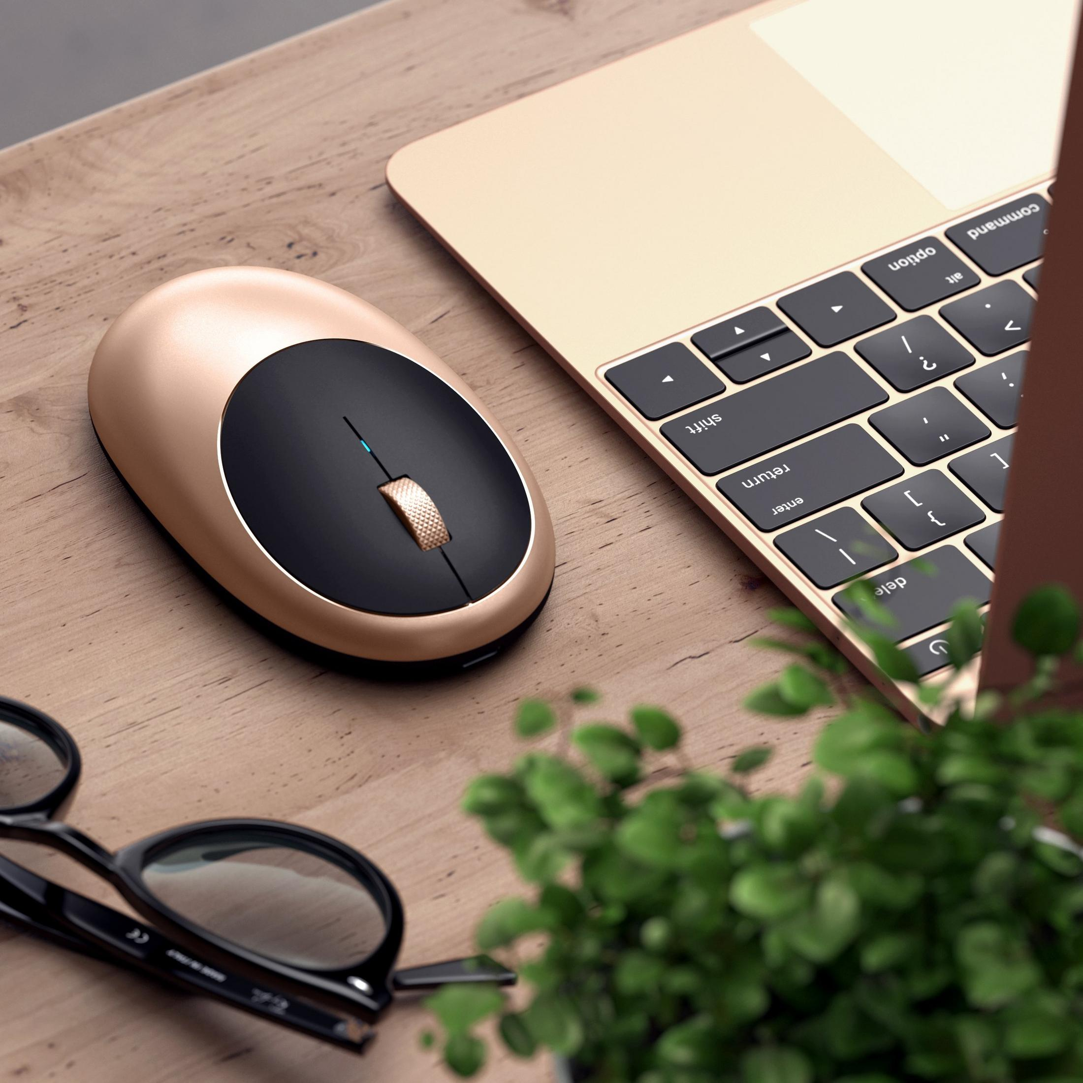 Goldene Maus neben Laptop-Tastatur und Brille auf Holztisch.