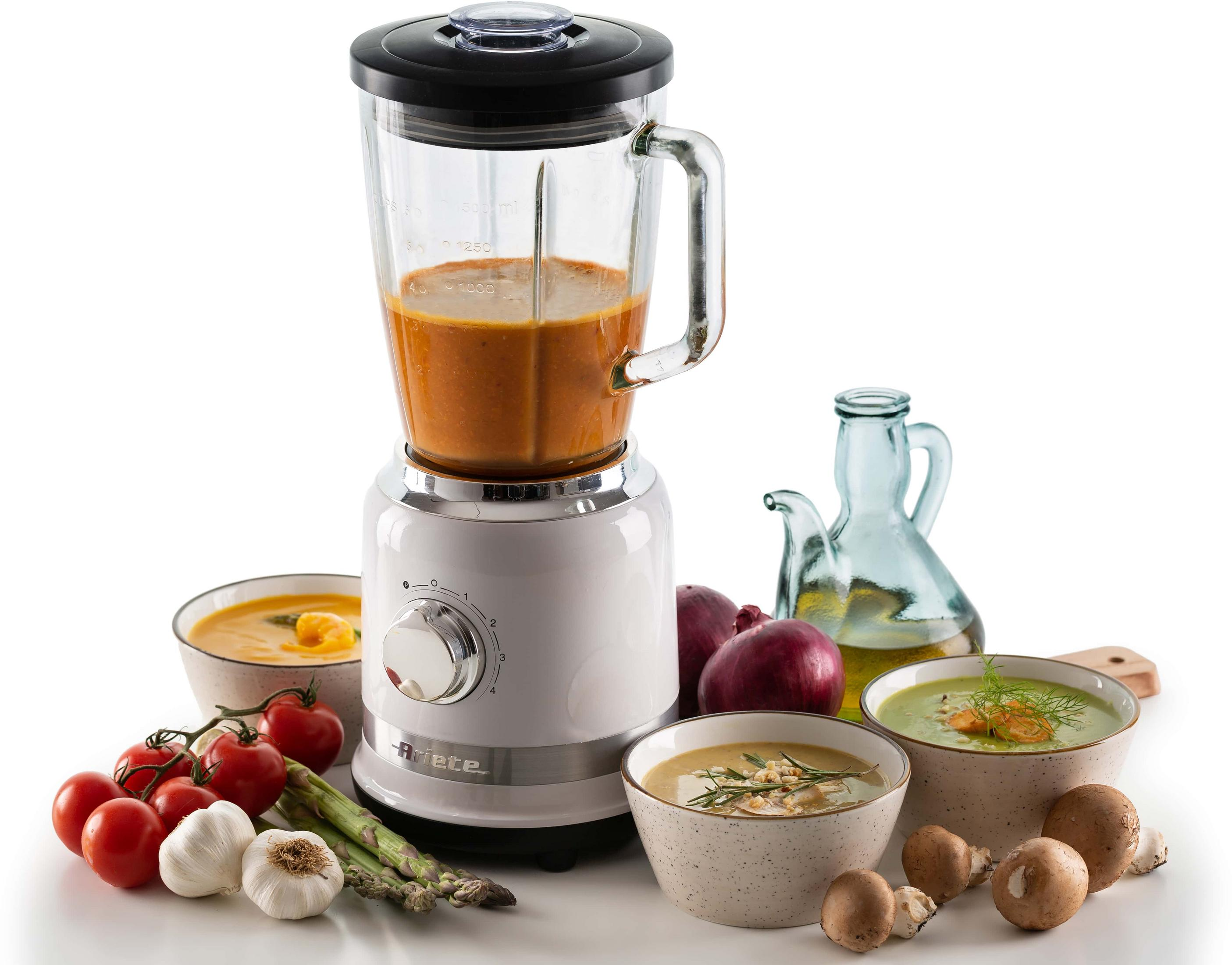 Een witte blender met oranje inhoud, omringd door soepkommen, groenten en champignons.