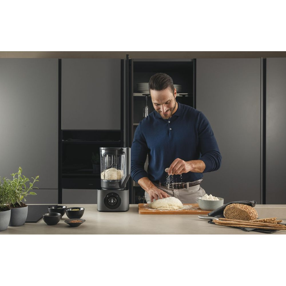 Un uomo cosparge farina sull'impasto, con un mixer nelle vicinanze.