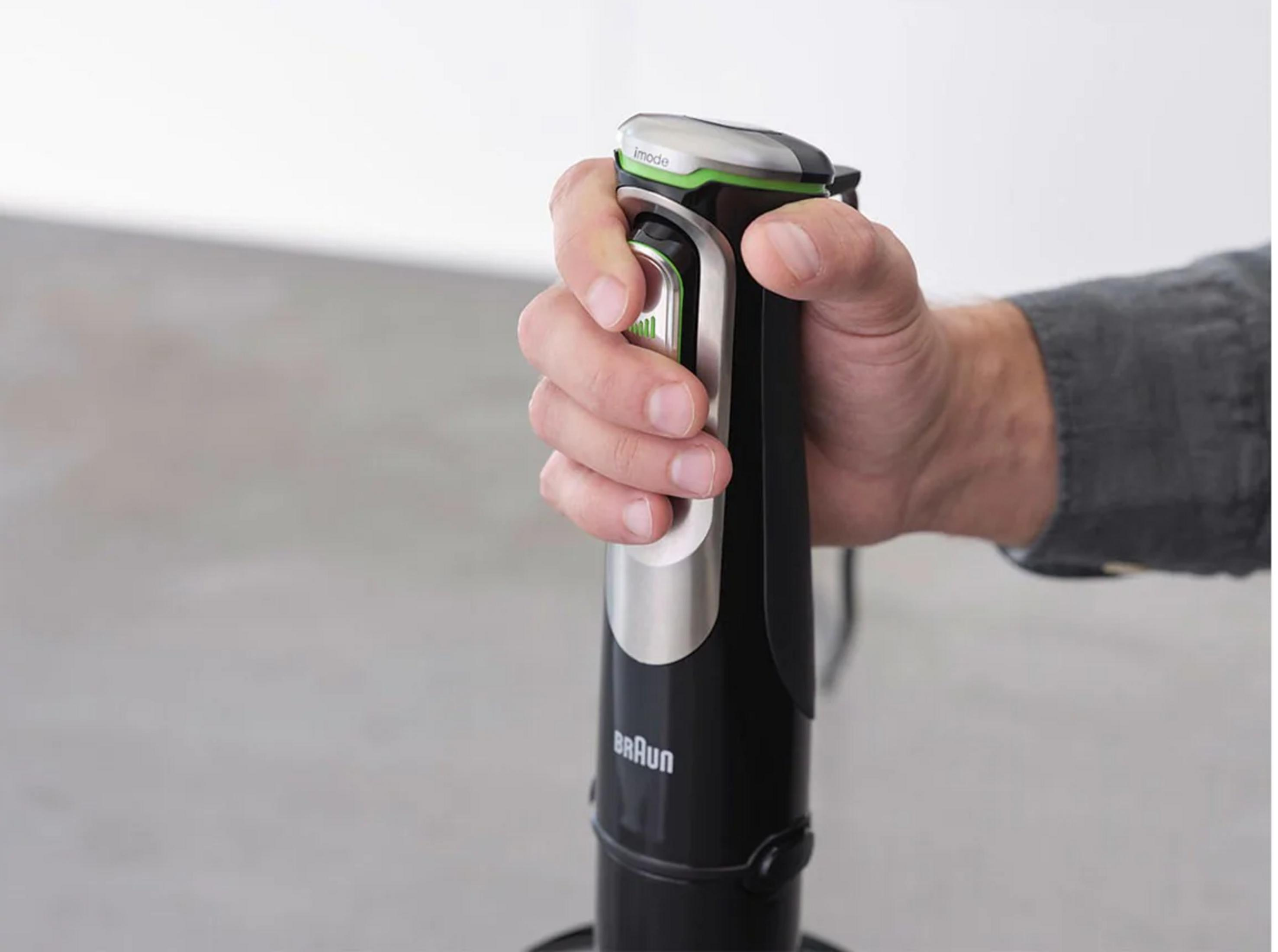 Dłoń trzymająca czarny blender ręczny z srebrnymi i zielonymi akcentami.