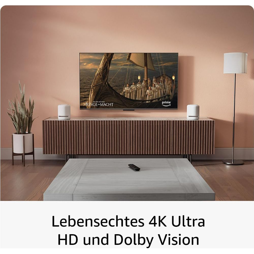 Ein Fernseher zeigt „Ringe der Macht“ über einem Holzschrank. Dazu ein Sofa und Lampe.
