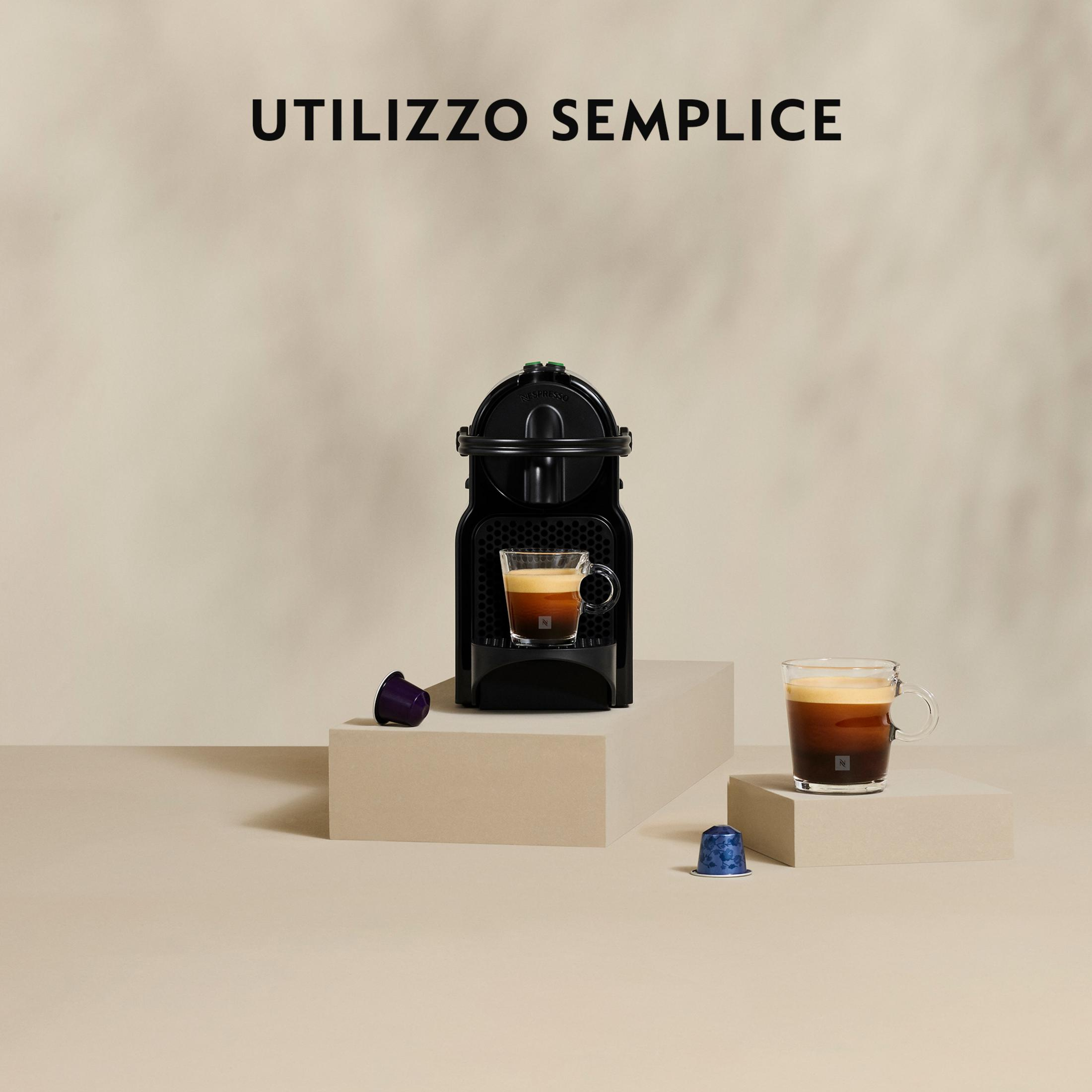 Eine schwarze Kaffeemaschine mit zwei Tassen Kaffee und Kapseln.