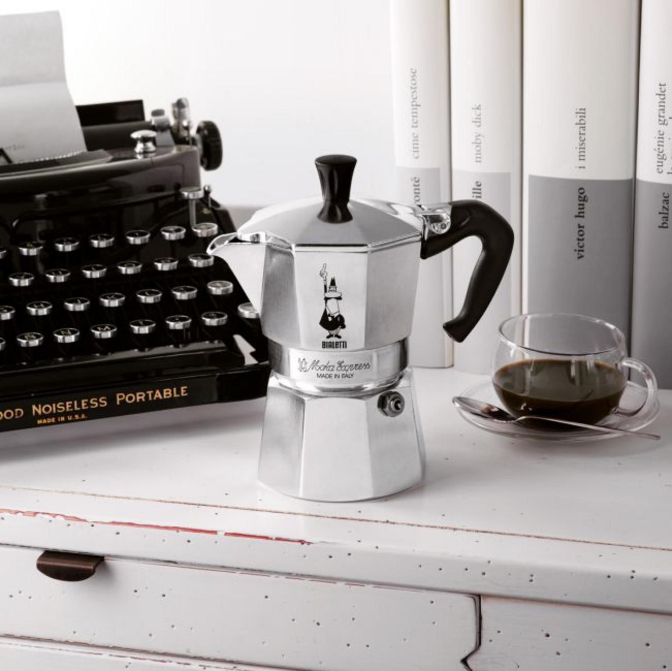 Srebrna kawiarka obok starej maszyny do pisania i książek.