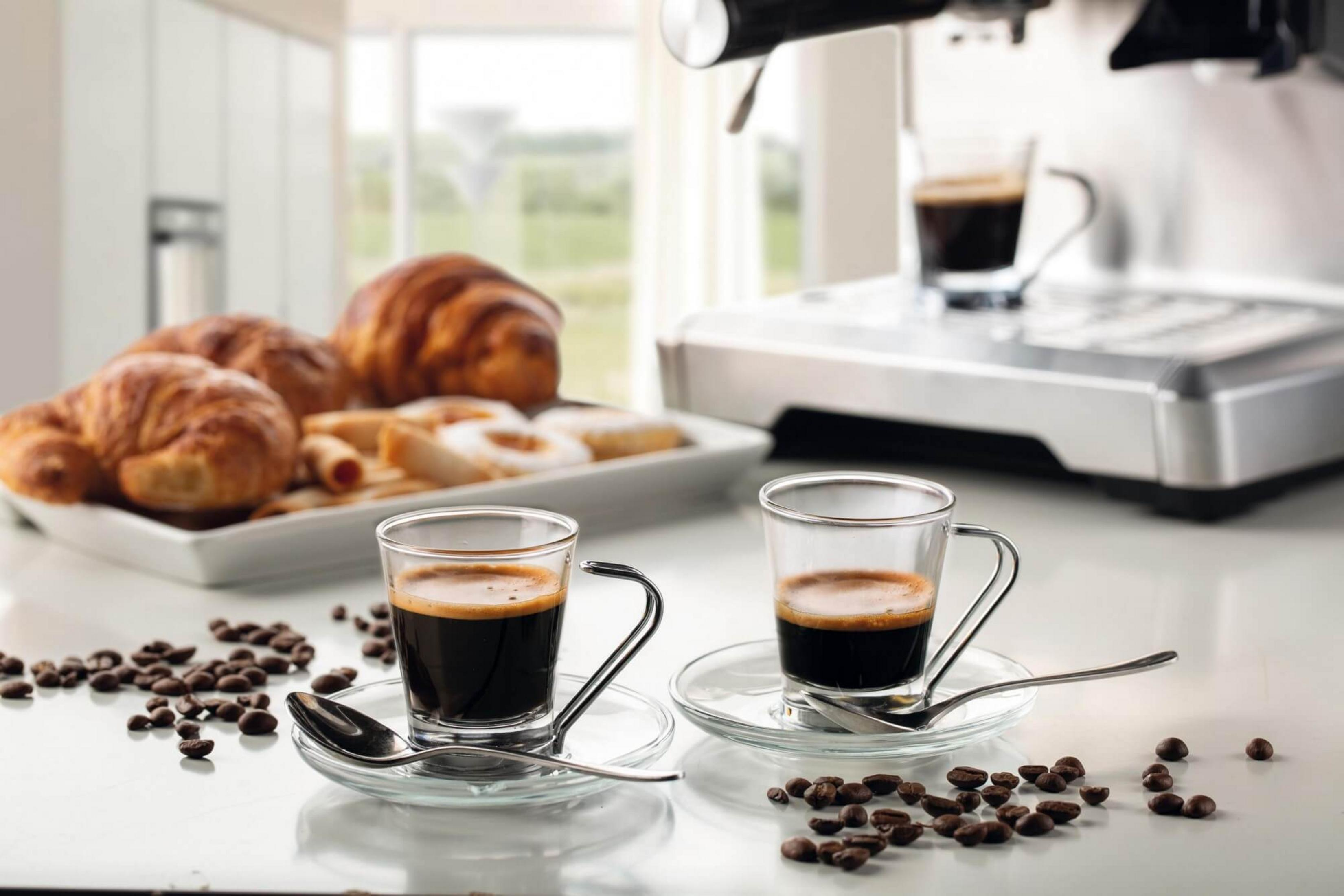 Dos tazas de espresso con pasteles y granos de café.