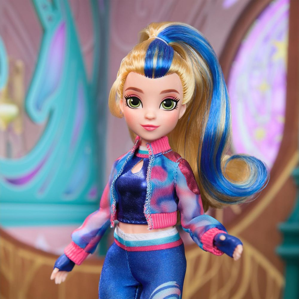 Lalka z blond włosami i niebieskimi pasemkami, nosi kolorową kurtkę i niebieskie spodnie.