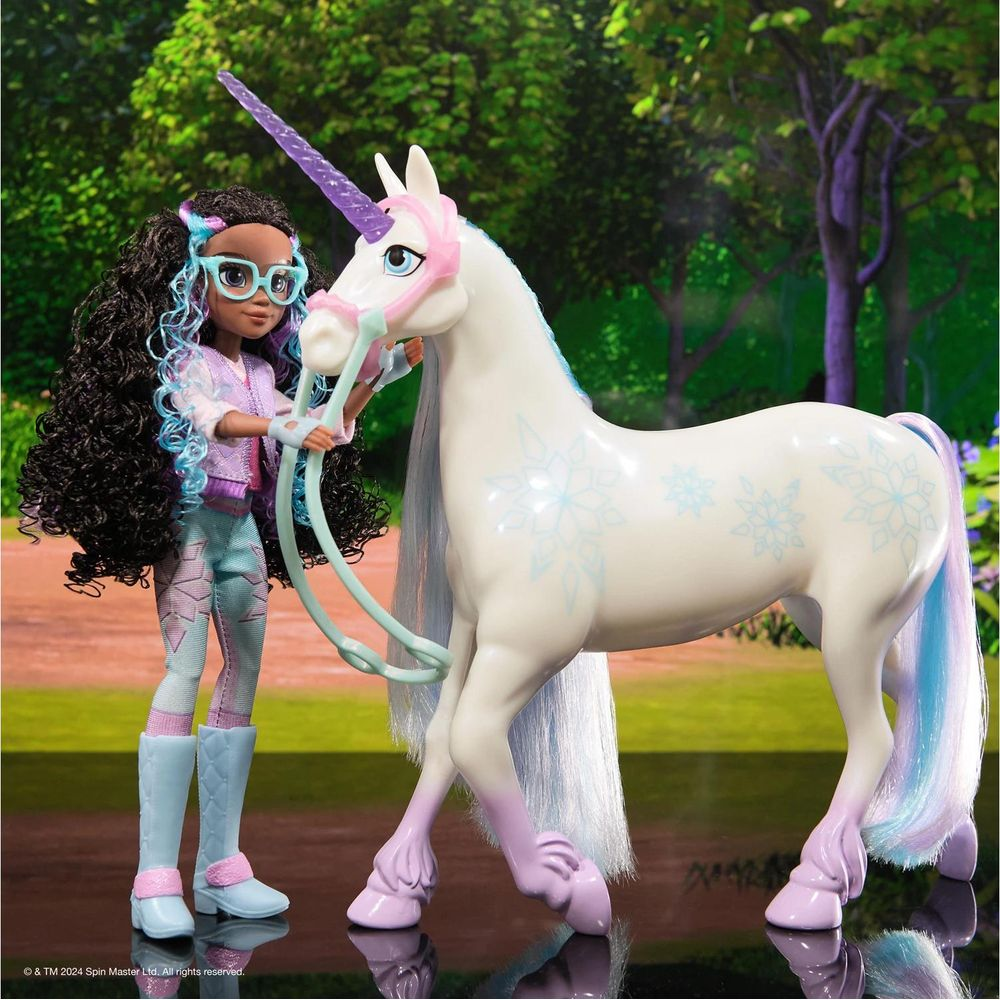 Una niña con pelo oscuro y rizado y gafas azules sostiene un unicornio blanco con cuerno morado.
