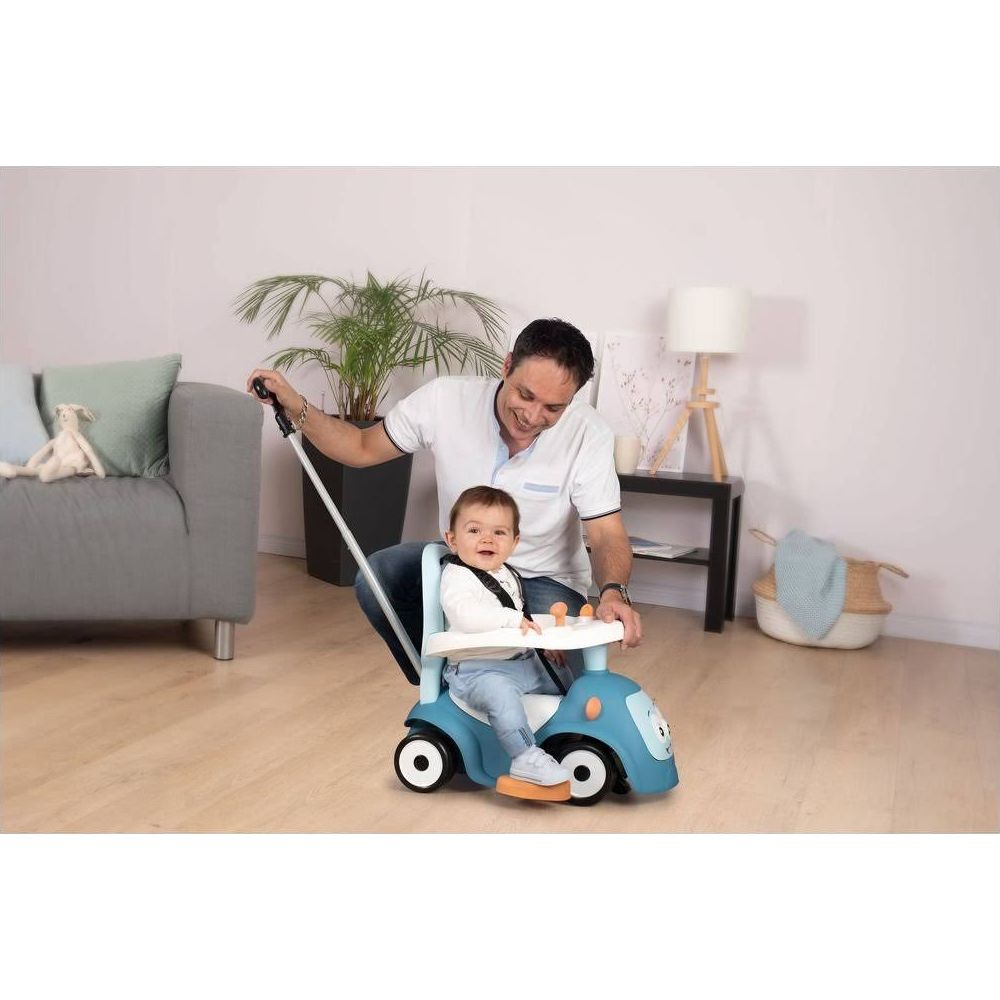 Mężczyzna pcha niebieski samochodzik z dzieckiem w środku. Wewnątrz.