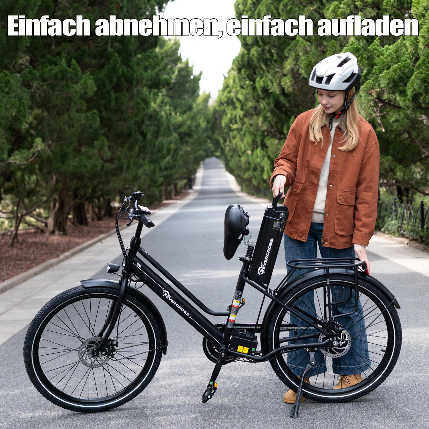 Una mujer con casco retira la batería de una bicicleta eléctrica negra en una carretera.