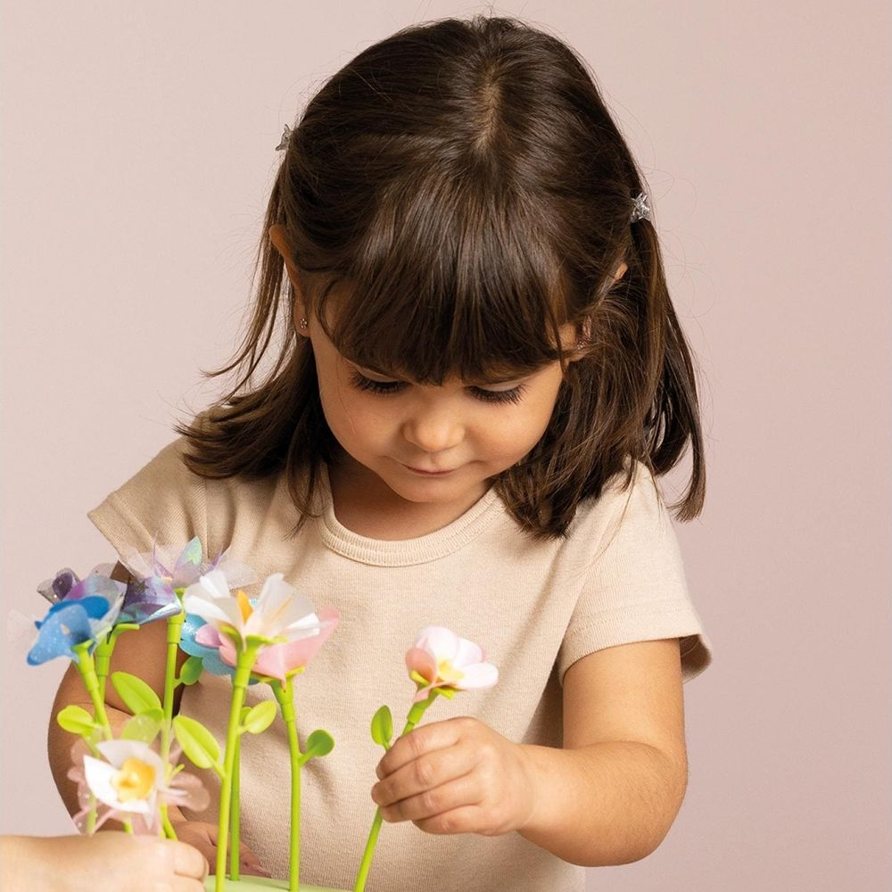 Dziewczynka z brązowymi włosami bawi się kolorowymi kwiatami z tkaniny.
