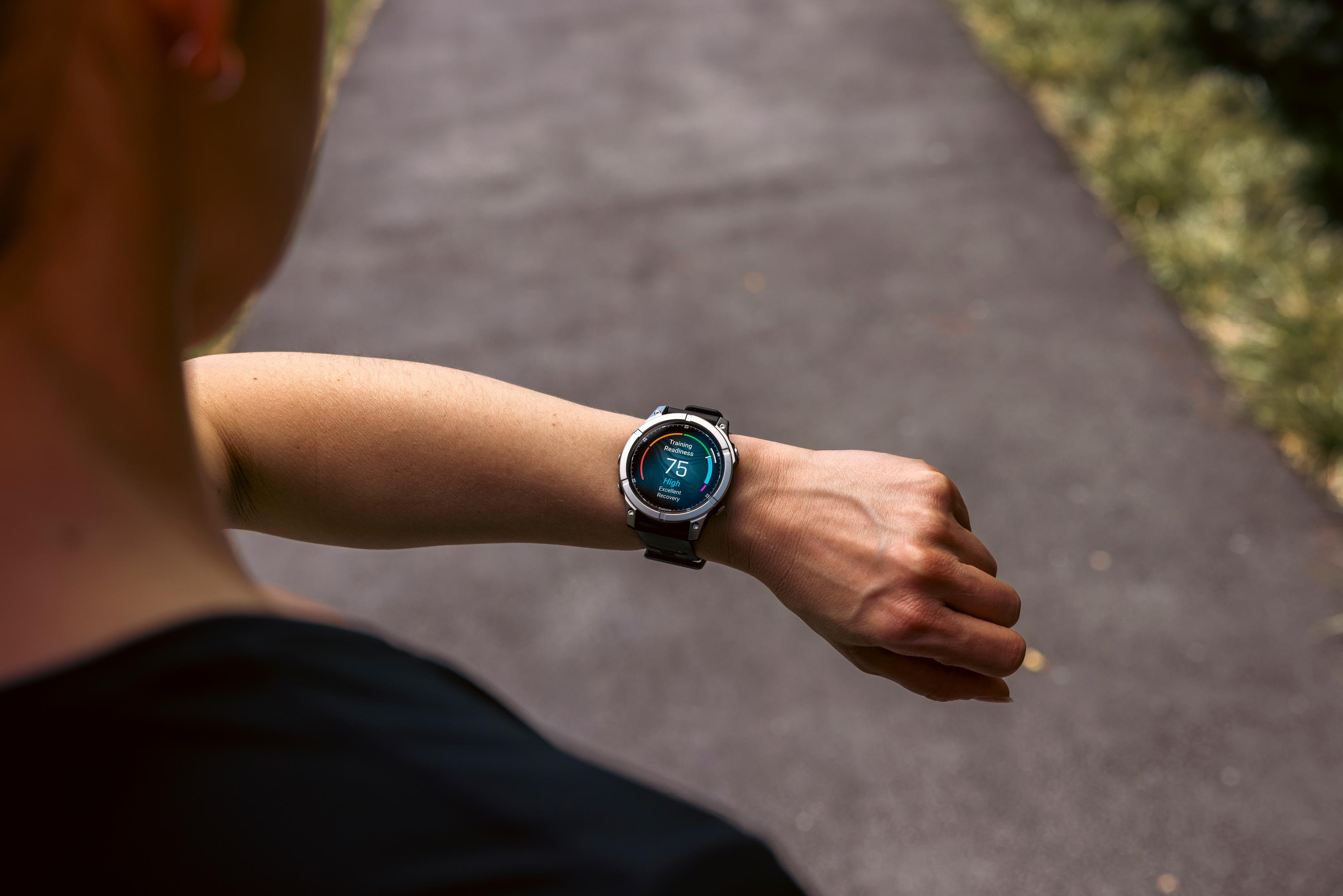 Osoba sprawdza smartwatch na nadgarstku pokazujący gotowość do treningu.