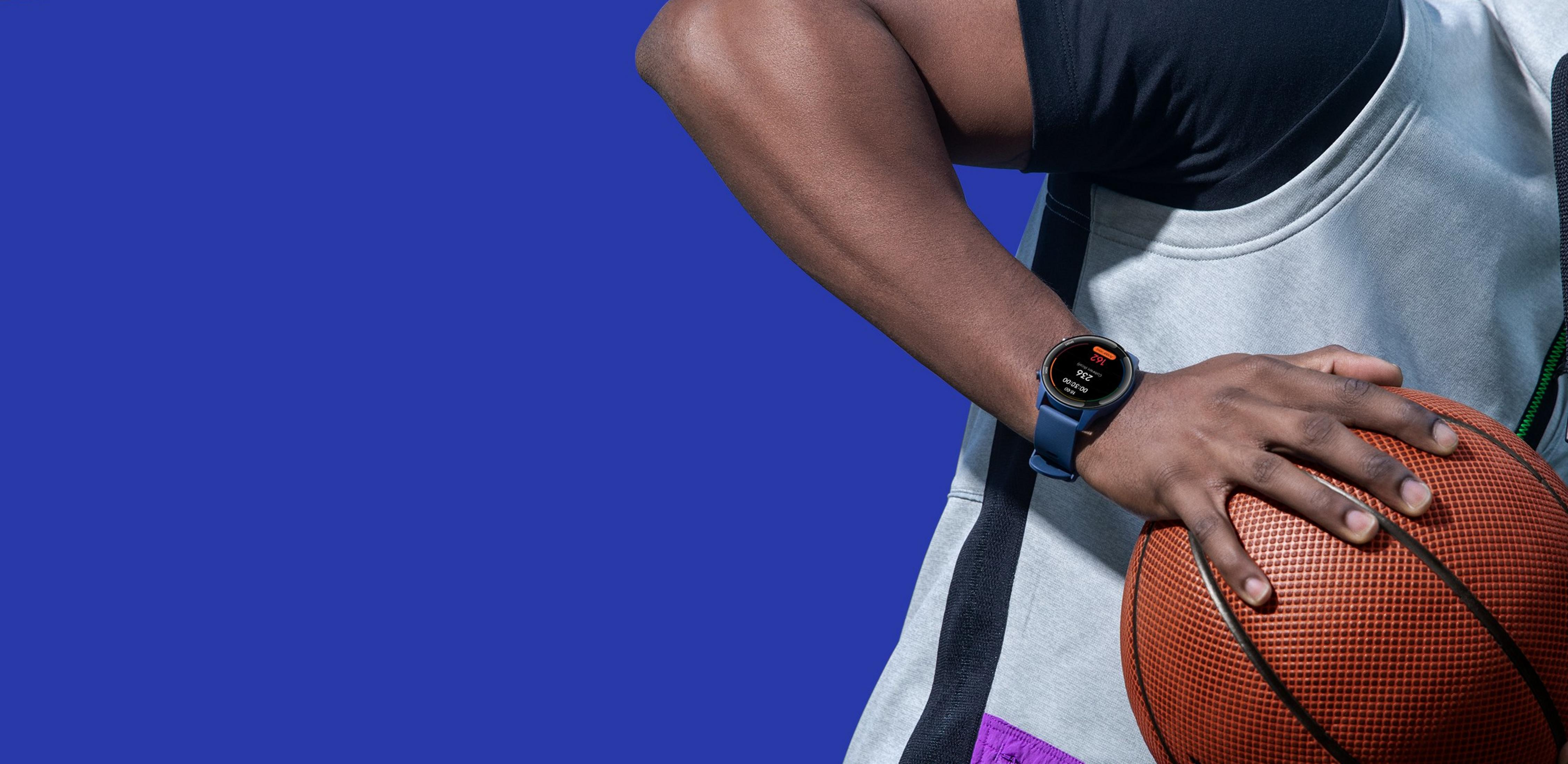 Ramię w smartwatchu trzyma piłkę do koszykówki na niebieskim tle.