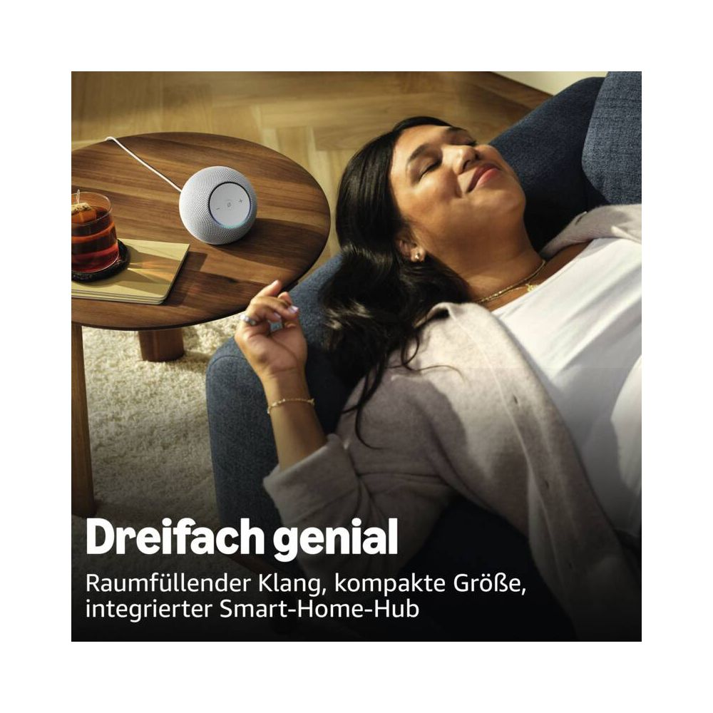 Frau entspannt auf Sofa, neben ihr ein Smart Speaker und ein Glas Tee.