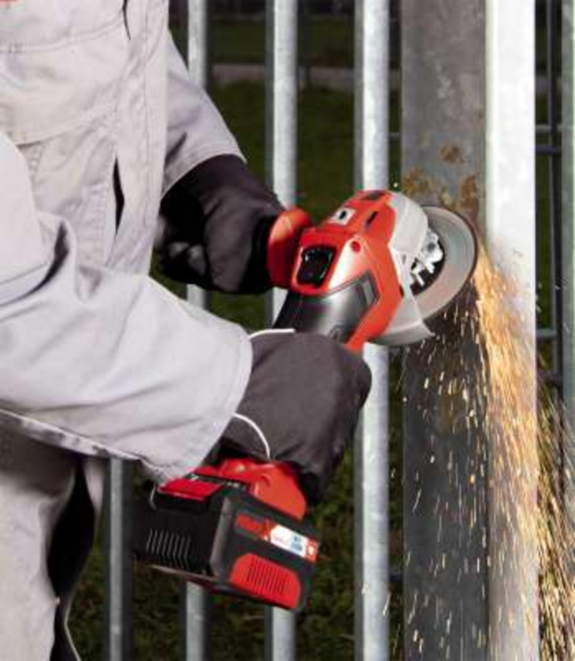 Osoba szlifuje metalowe słupki szlifierką kątową, lecą iskry.