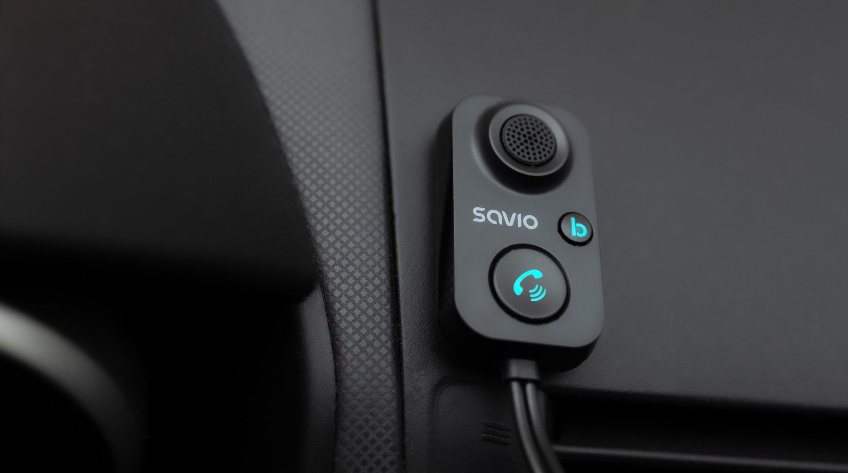 Czarna deska rozdzielcza samochodu z adapterem Bluetooth Savio i podświetlanym przyciskiem połączenia.
