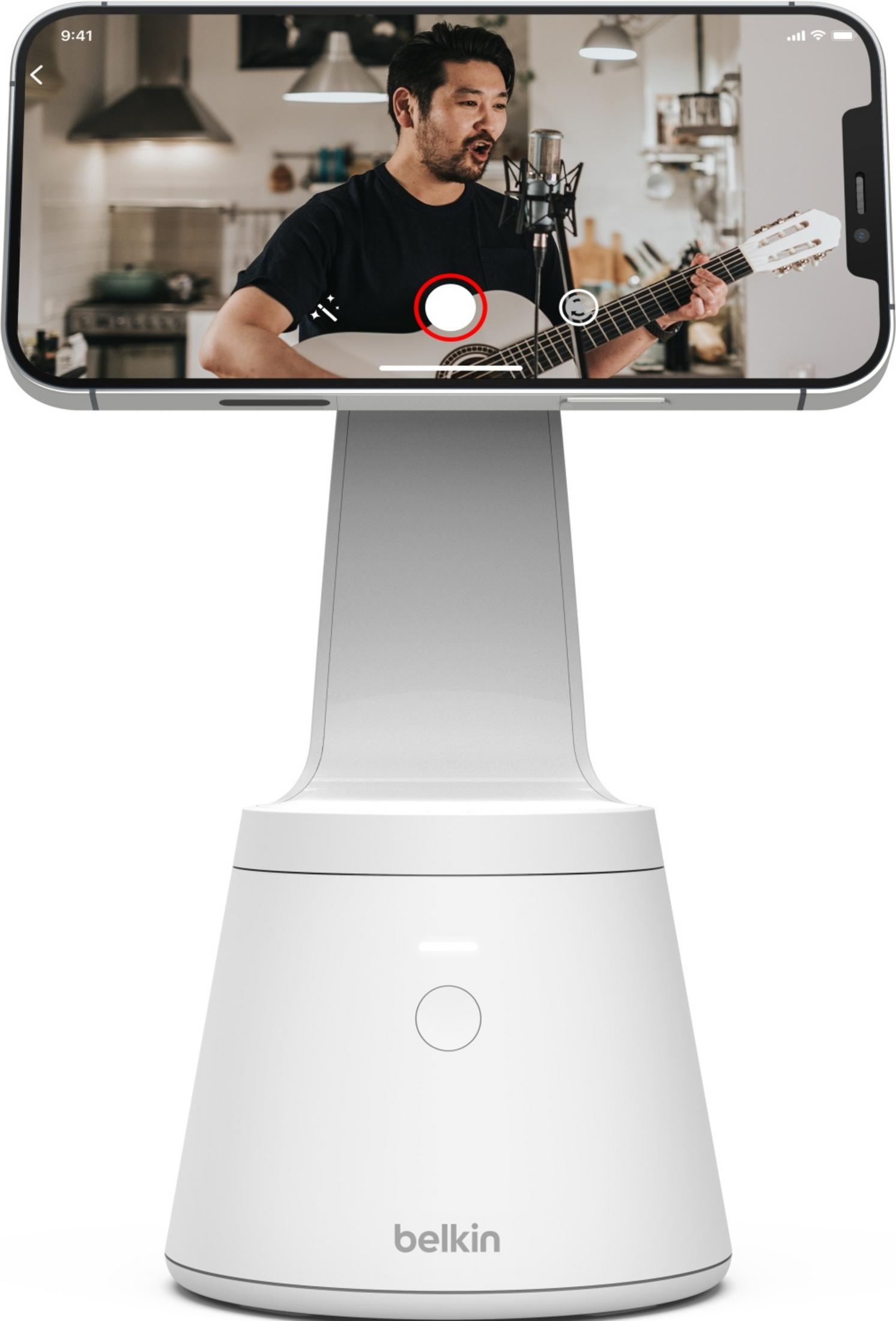 Hombre toca la guitarra y canta en un micrófono en un soporte blanco.
