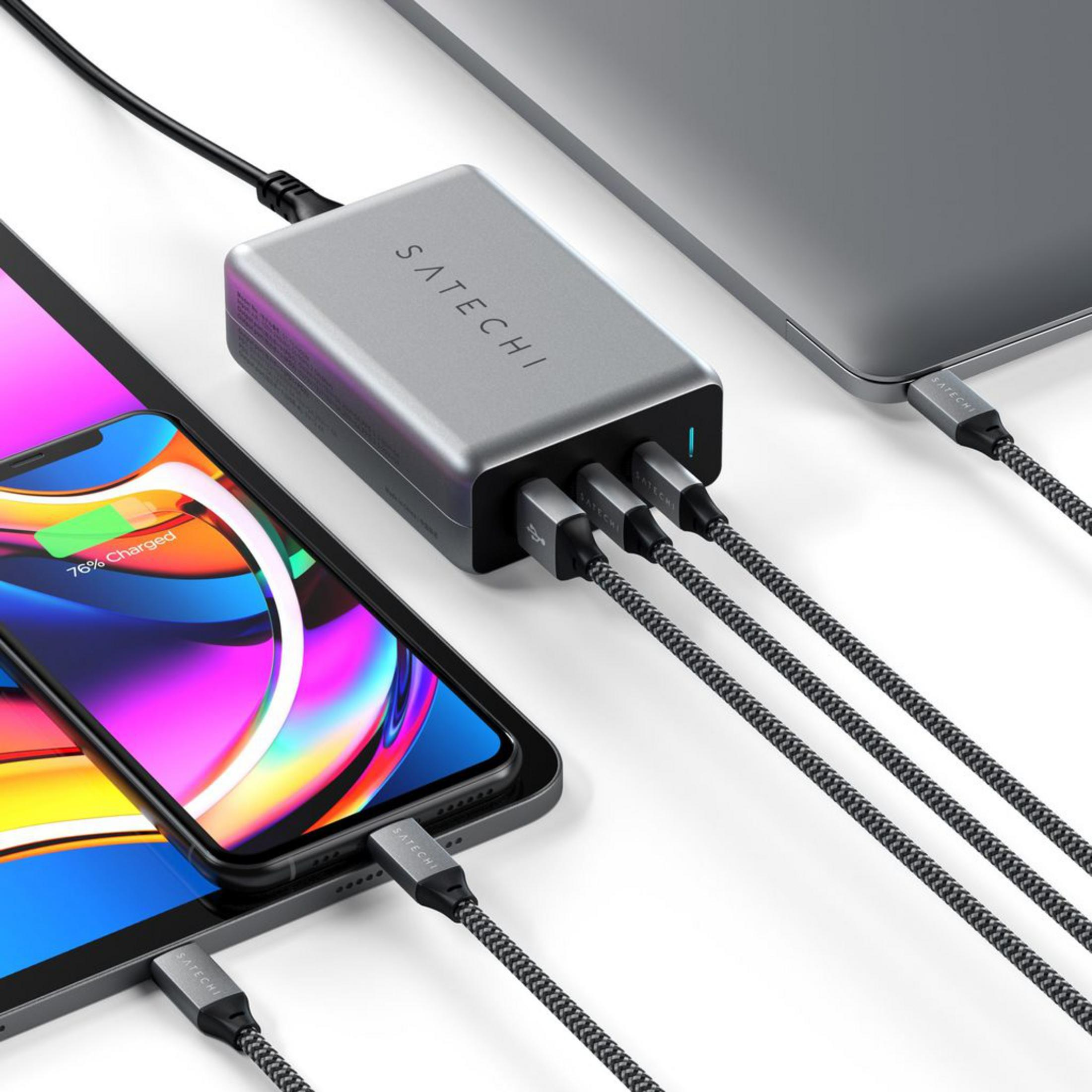 Un cargador Satechi gris carga un iPhone y un portátil, conectado por tres cables.