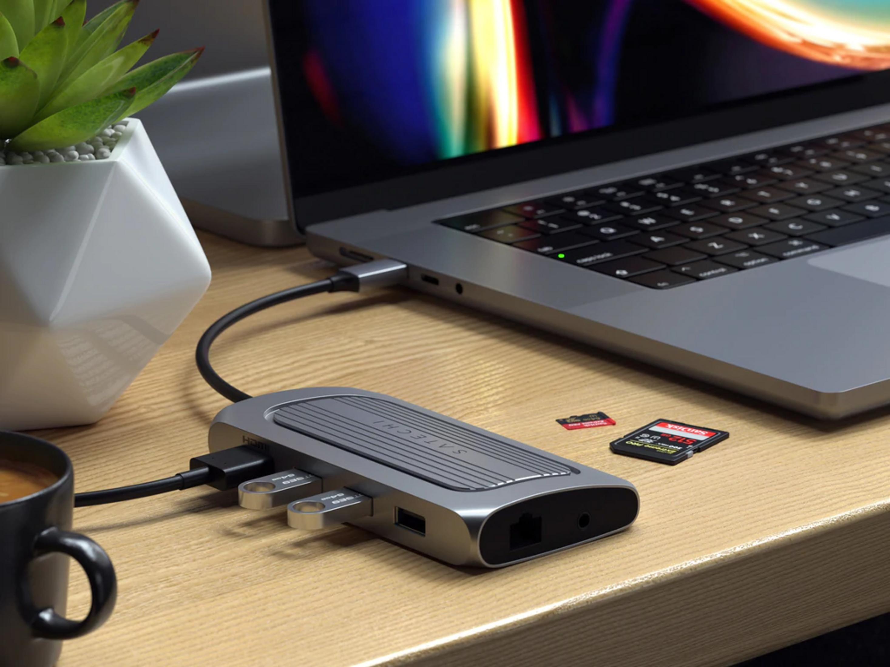 Ein Laptop-Hub mit USB-Sticks, SD-Karte, Kaffeetasse und Pflanze.