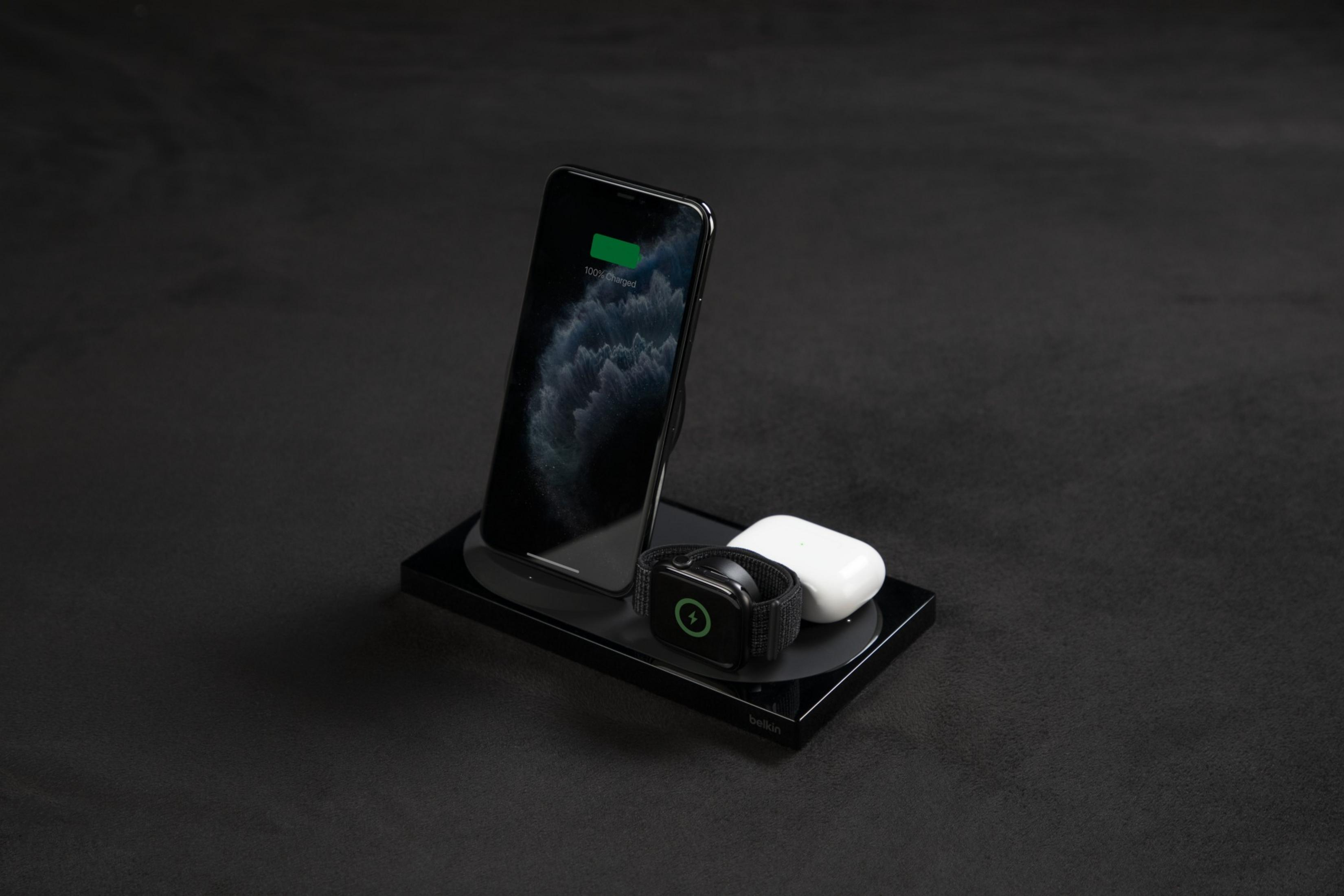 Ein Smartphone, eine Smartwatch und AirPods auf einer Ladestation.