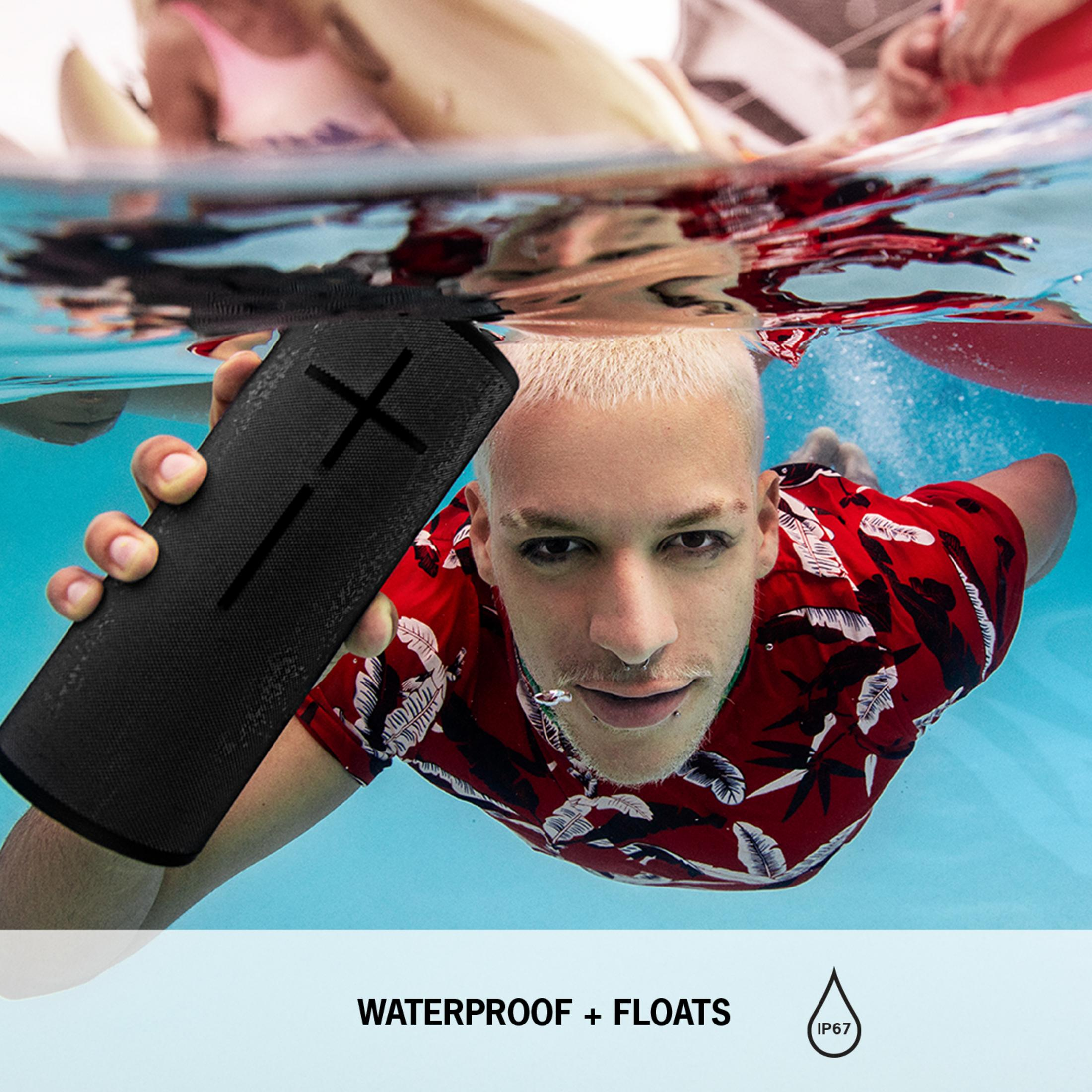 Hombre rubio sostiene altavoz negro impermeable en piscina azul.