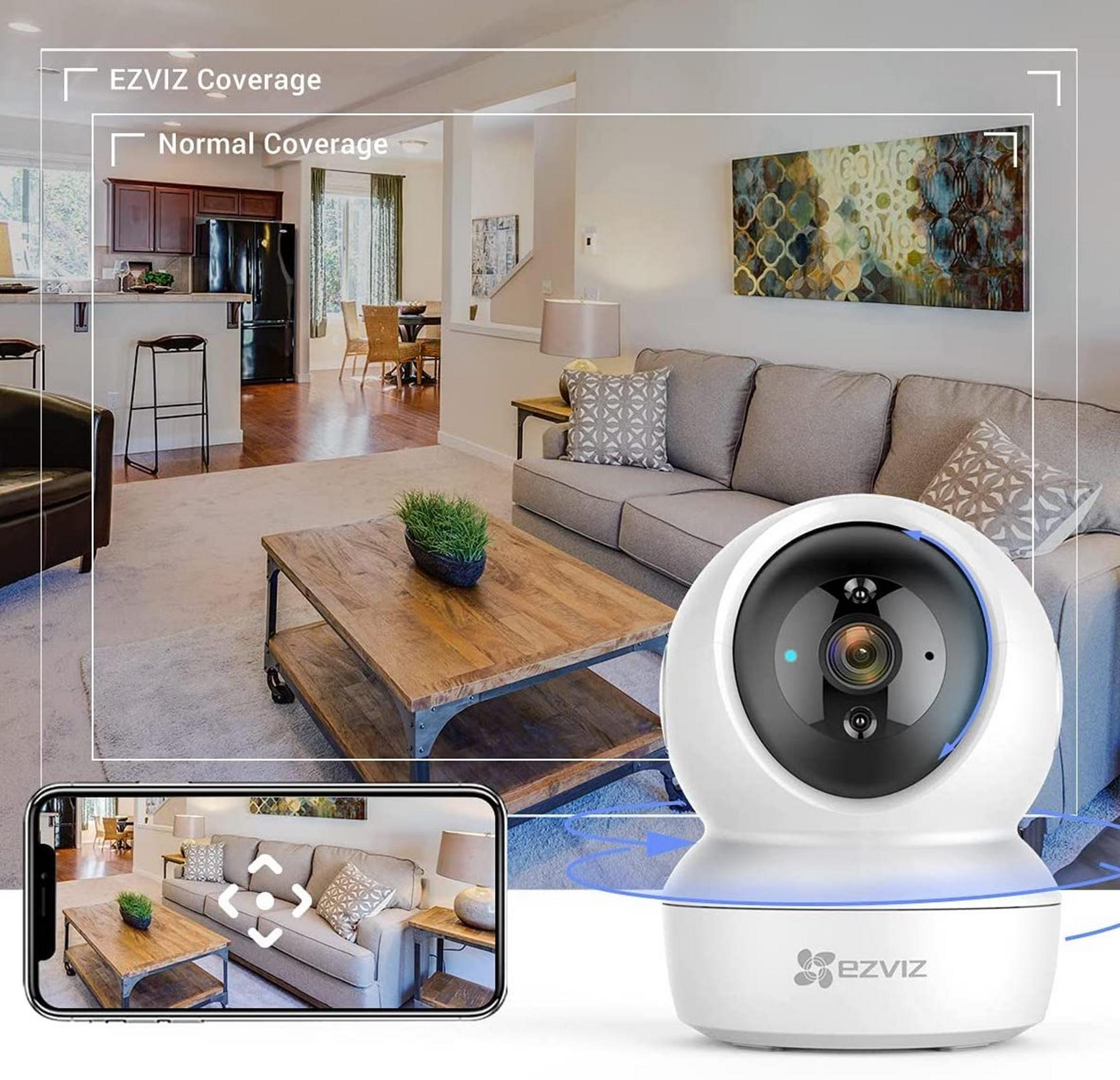 Una cámara de seguridad EZVIZ blanca en una sala de estar con sofá y mesa de centro.