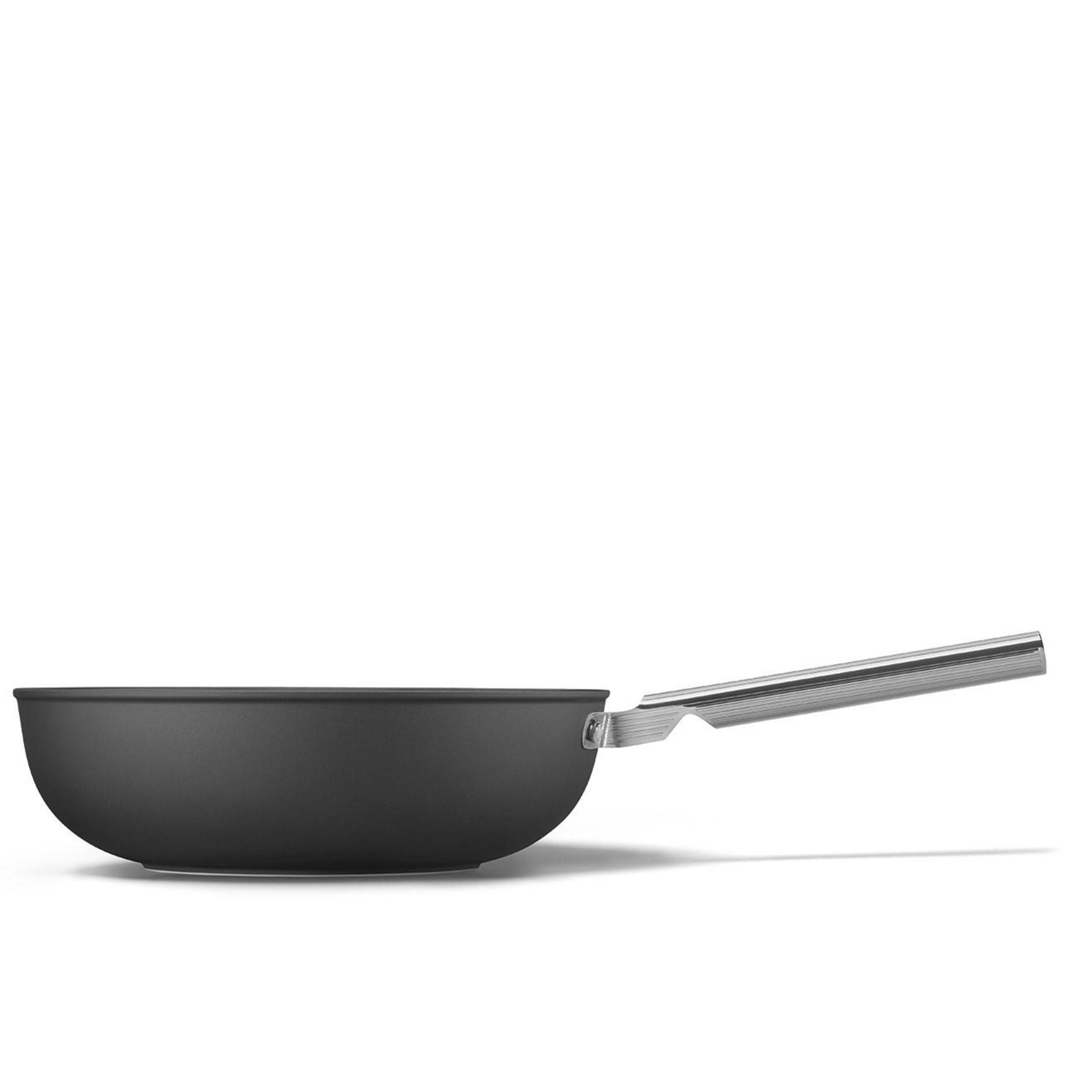 Una sartén negra con un largo mango plateado sobre fondo blanco.