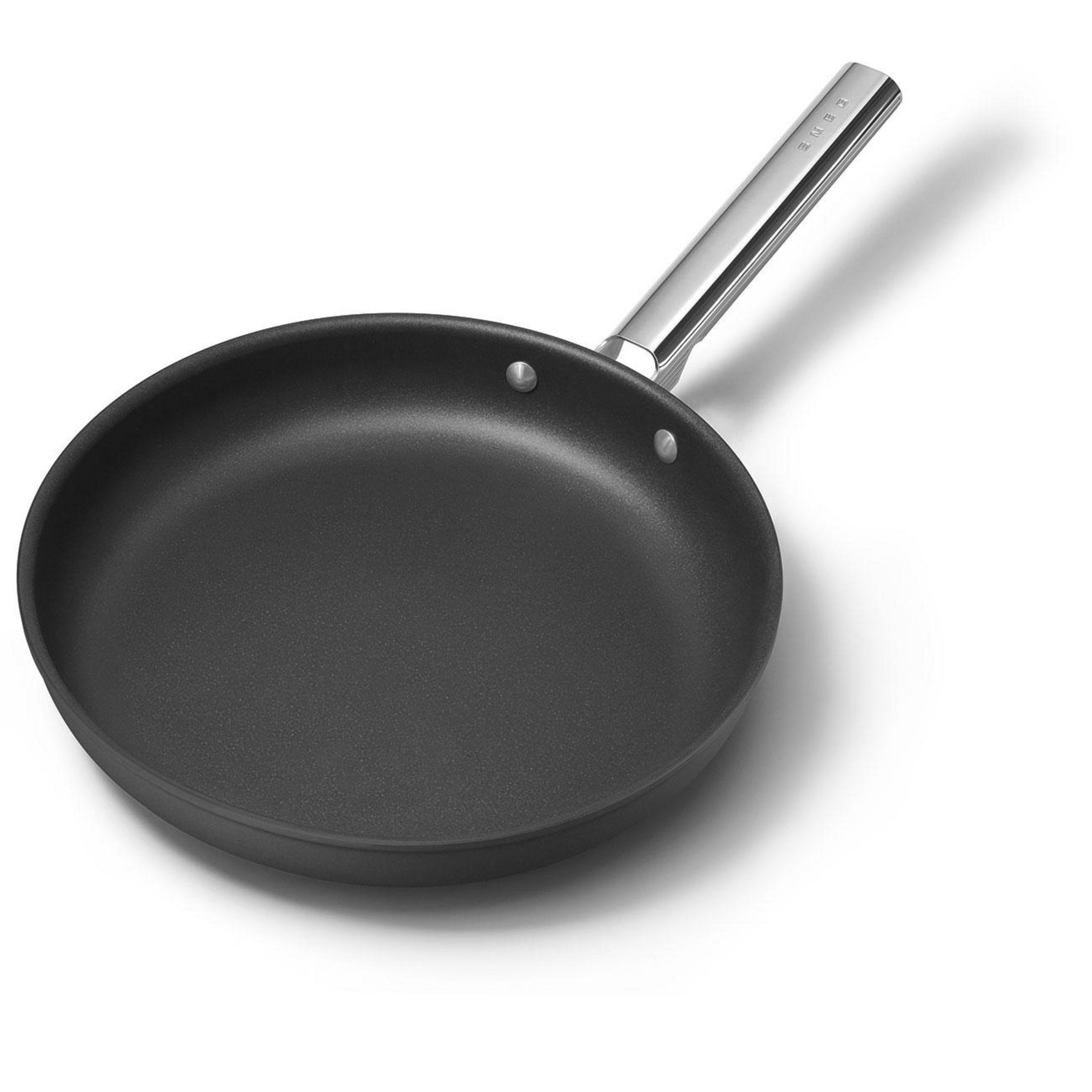 Parlak metal saplı siyah tava beyaz arka plan üzerinde.