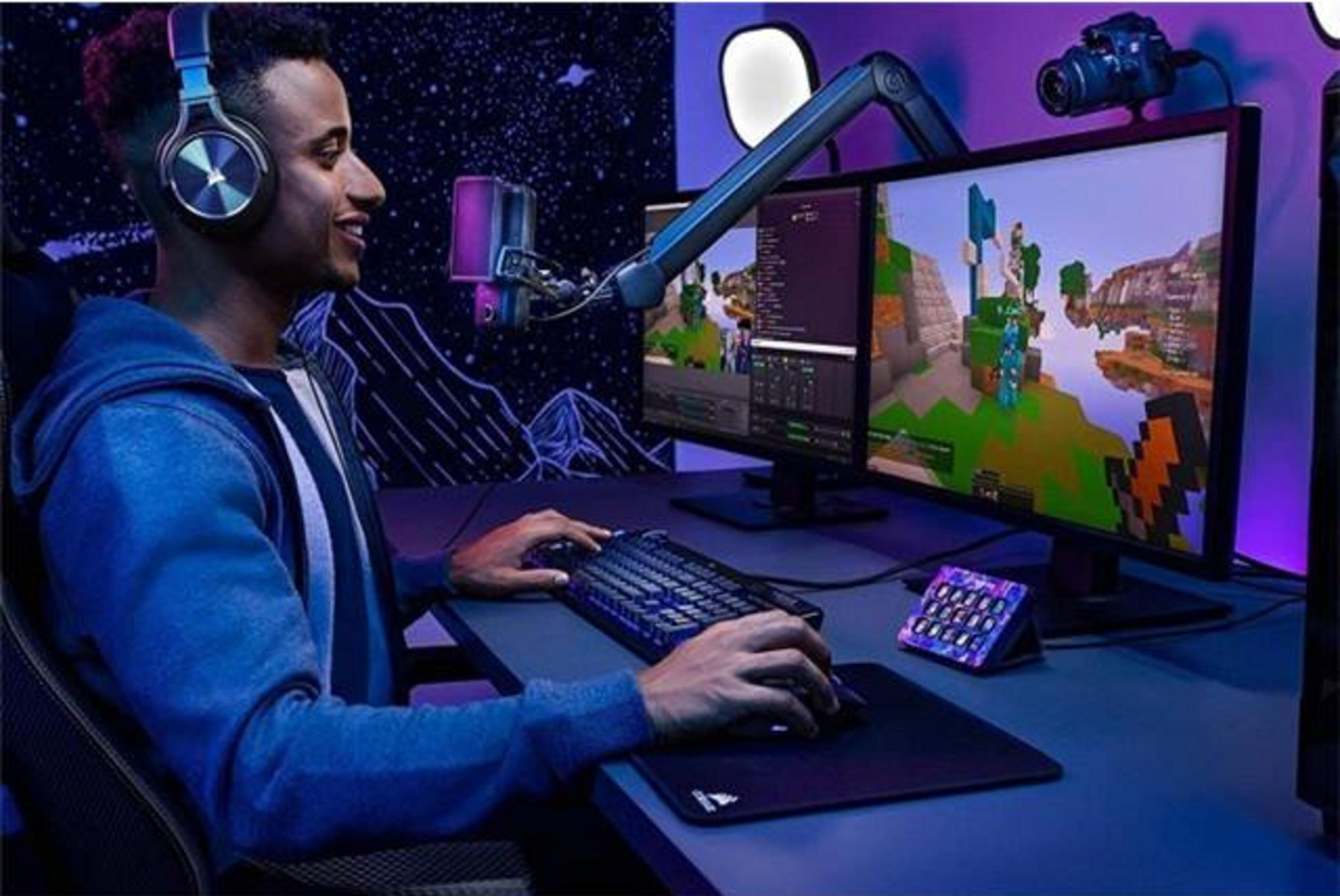 Mężczyzna w słuchawkach gra na komputerze z dwoma ekranami.