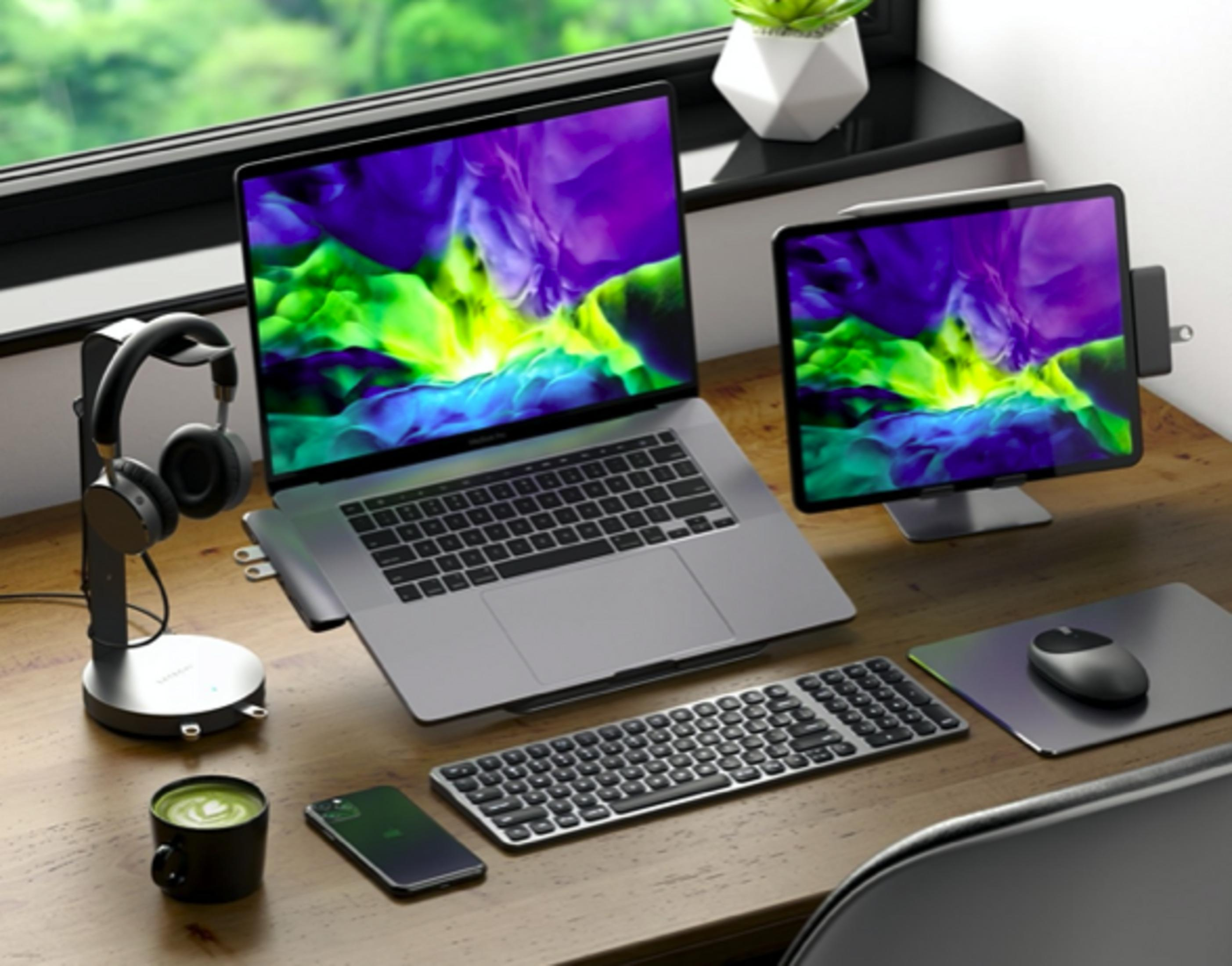 Una scrivania con laptop, tablet, cuffie, tazza e mouse.