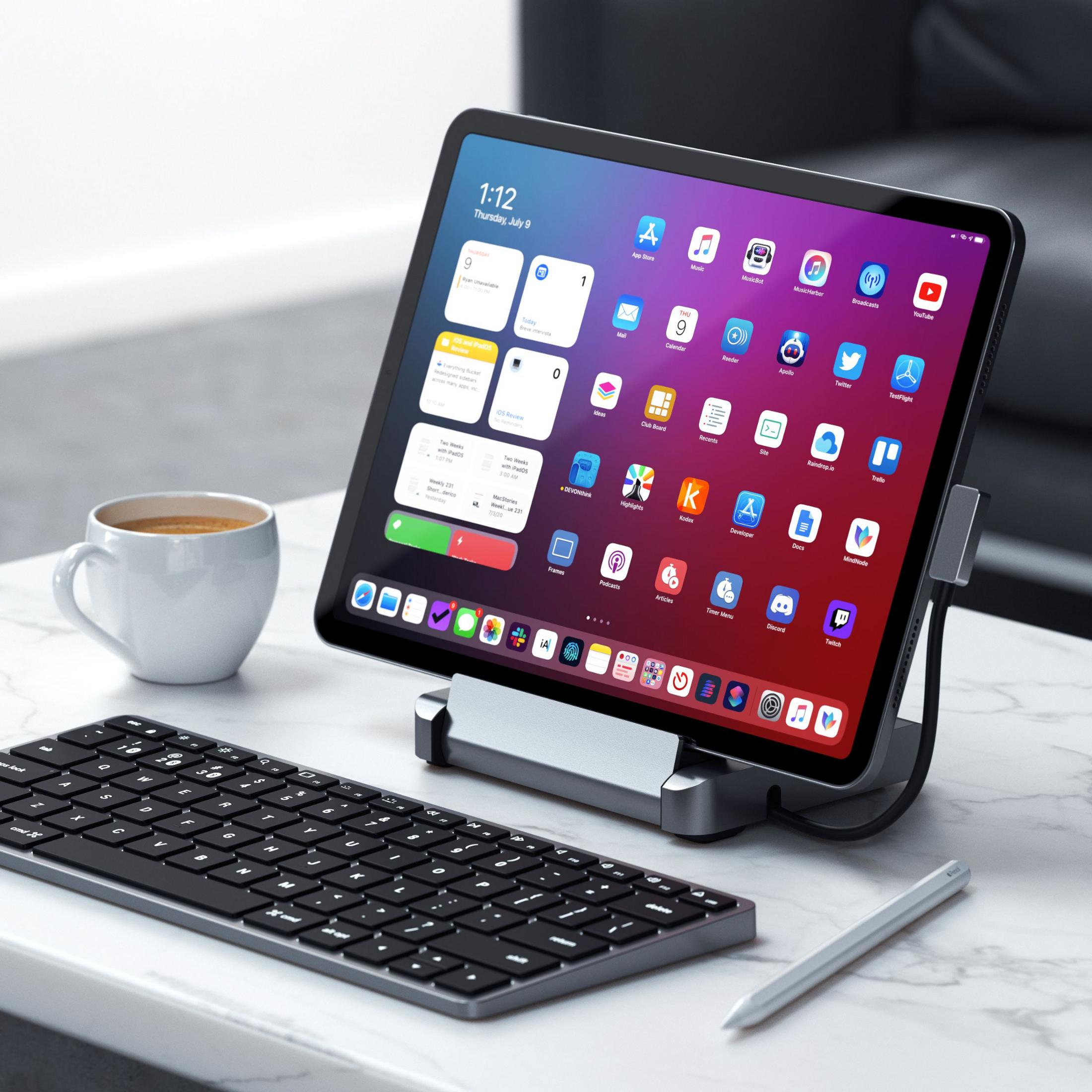Ein Tablet mit Apps, Tastatur, Stift und Kaffeetasse auf einem Marmortisch.