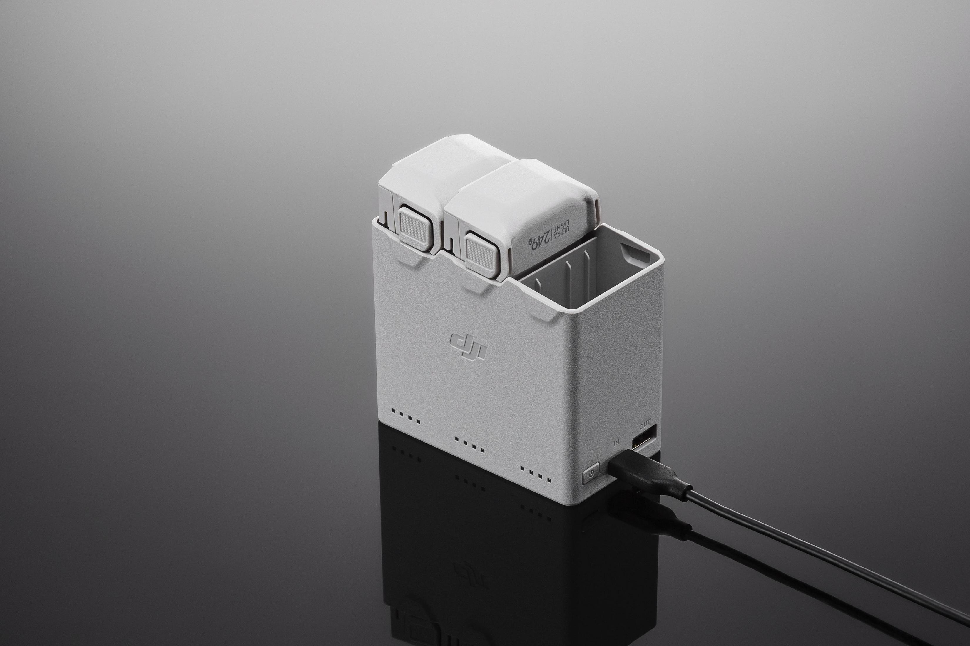 Ein weißes DJI Akkuladegerät mit zwei eingelegten Akkus, ein Kabel steckt in 