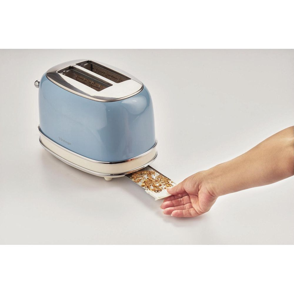 Ręka wyciąga tosta z niebieskiego, zabytkowego tostera.