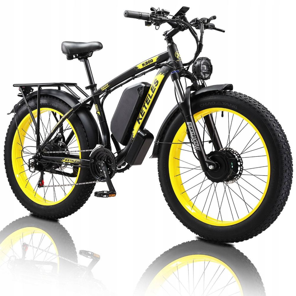 Bicicleta eléctrica negra con llantas amarillas, neumáticos anchos y batería.