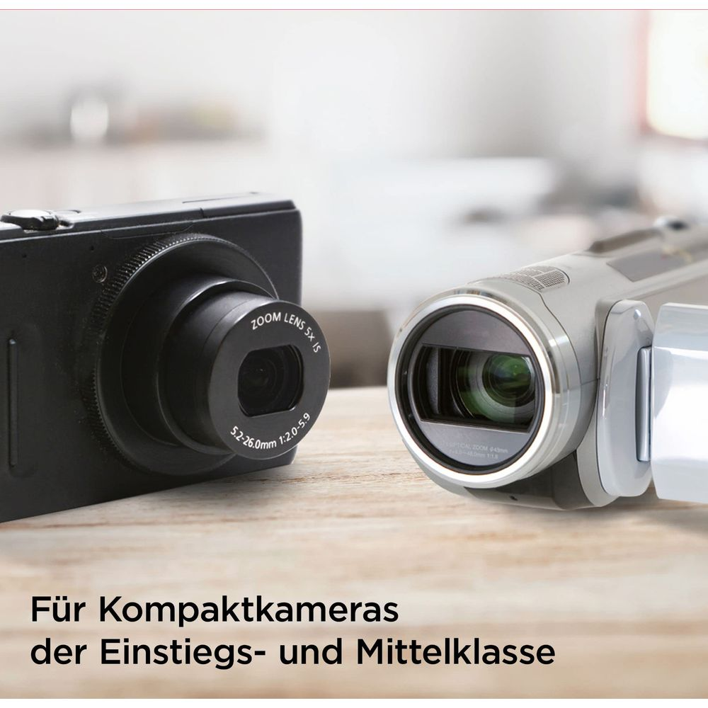 Due fotocamere su un tavolo di legno: una fotocamera digitale nera e una videocamera argentata.