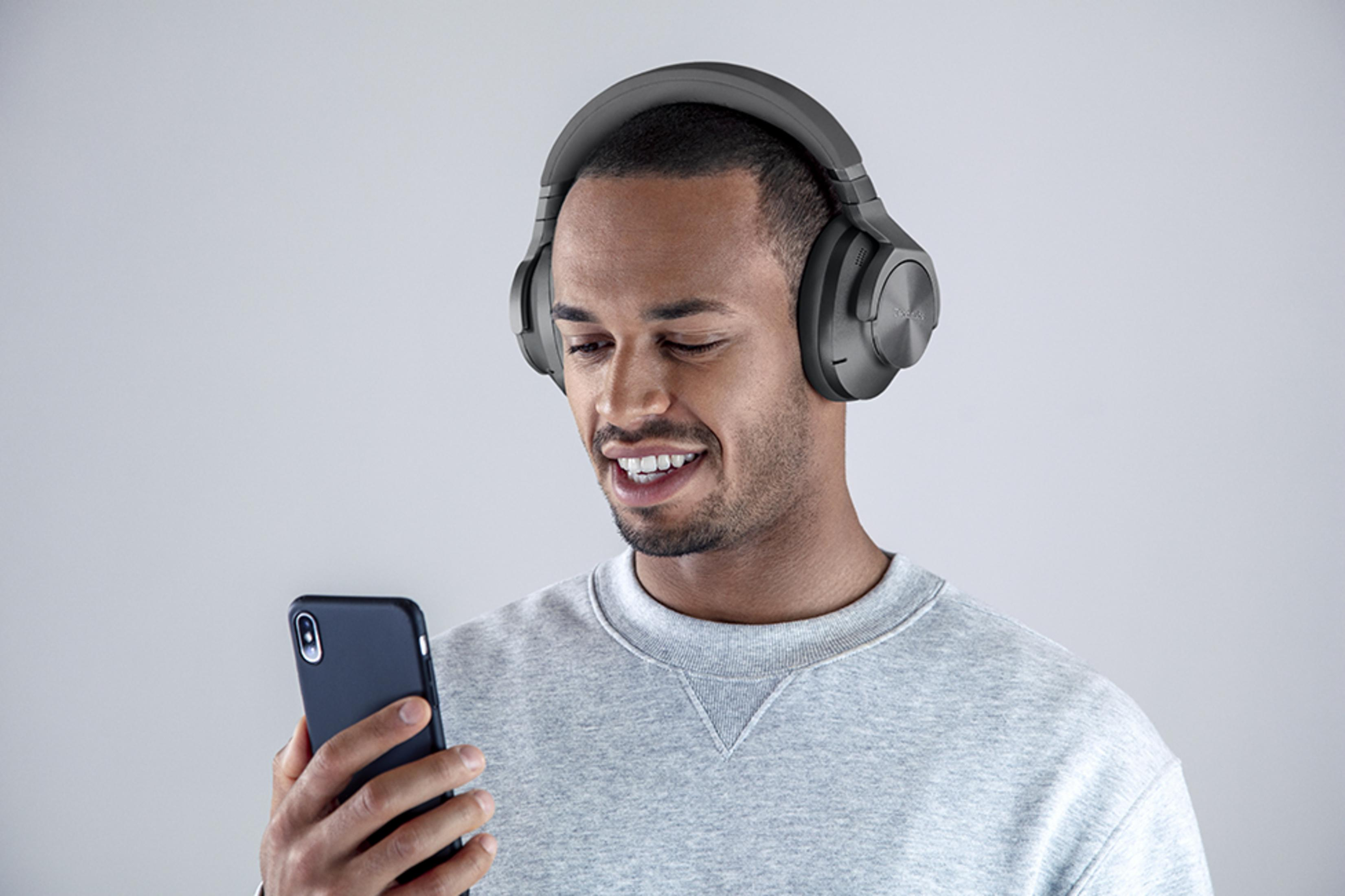 A man wearing headphones looks at his phone.