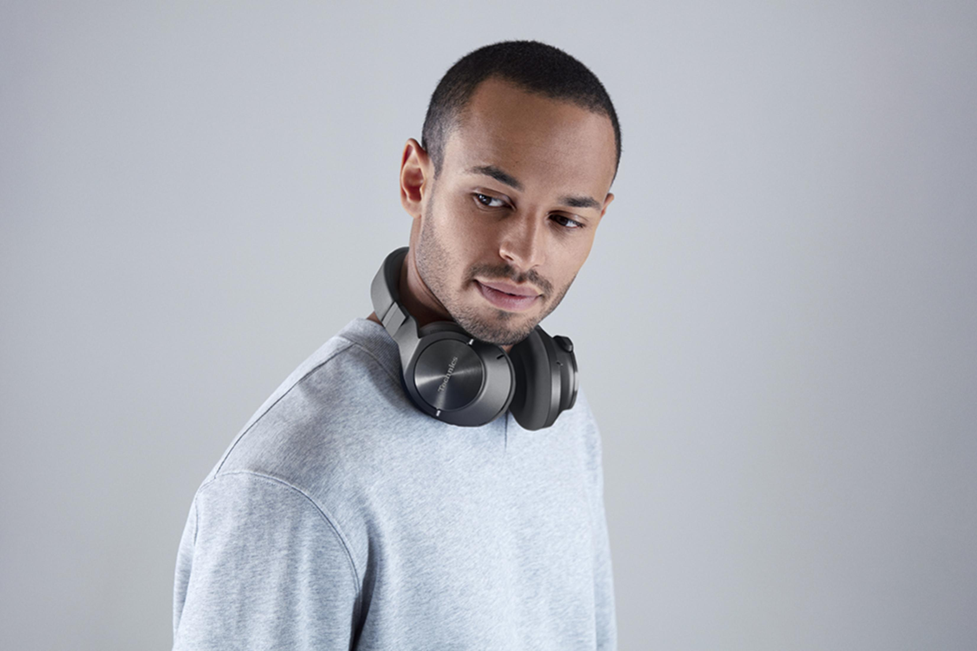 A man wearing headphones around his neck, dressed in a gray sweatshirt.