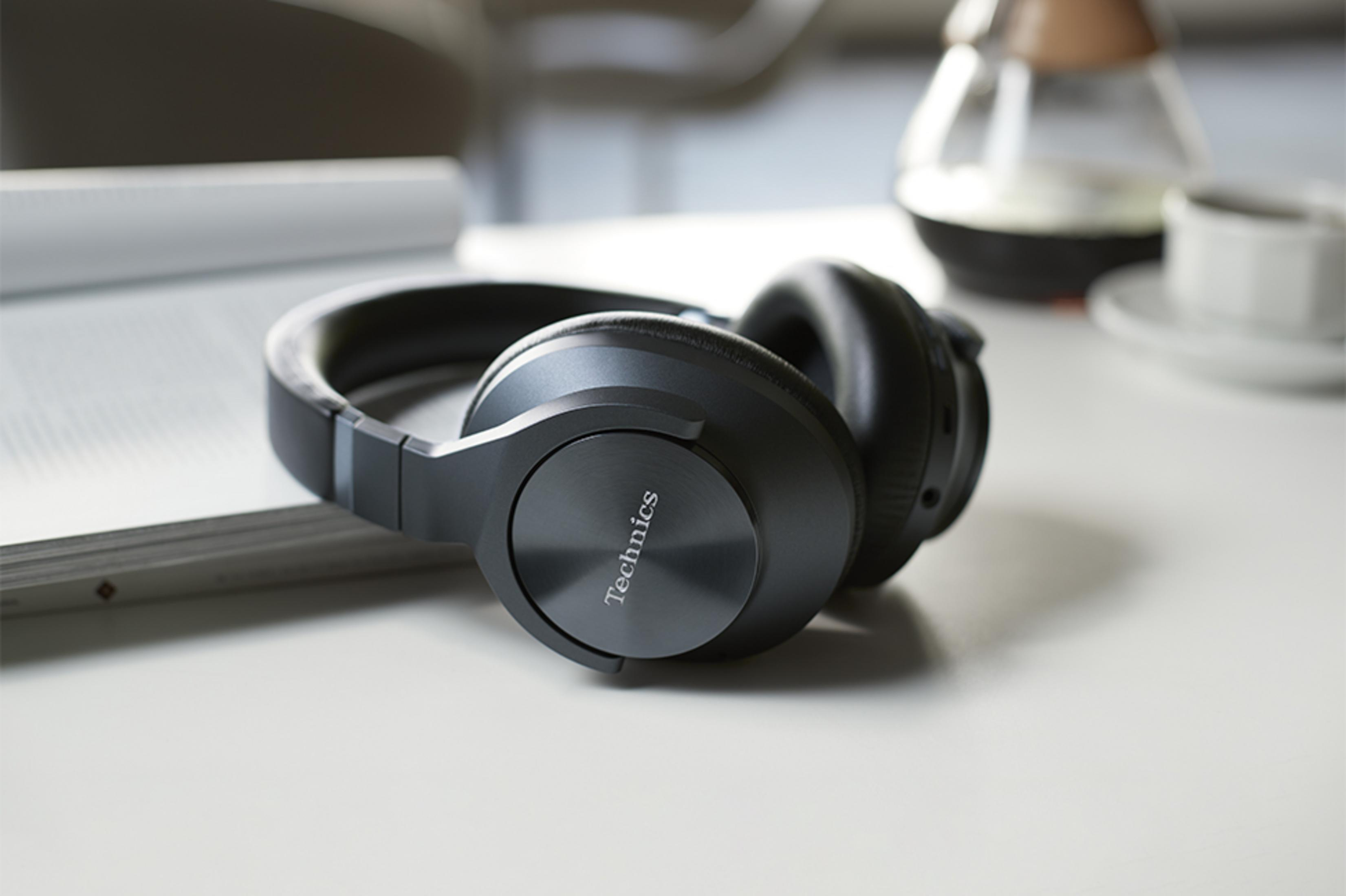 Black headphones with "Technics" logo resting on an open book.