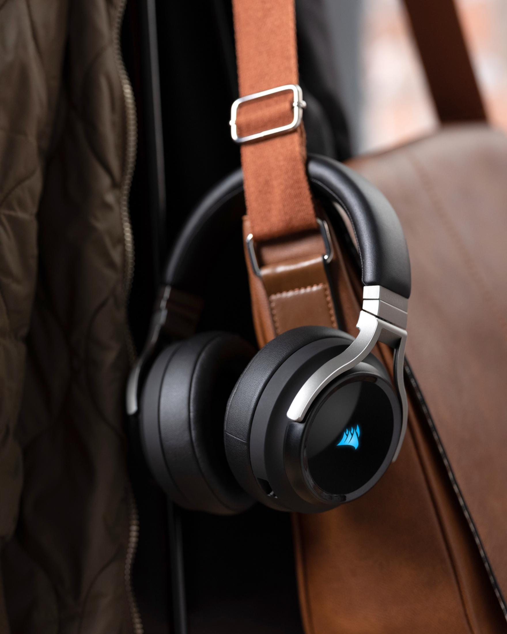 Czarne słuchawki z niebieskim logo wiszą na brązowej torbie.