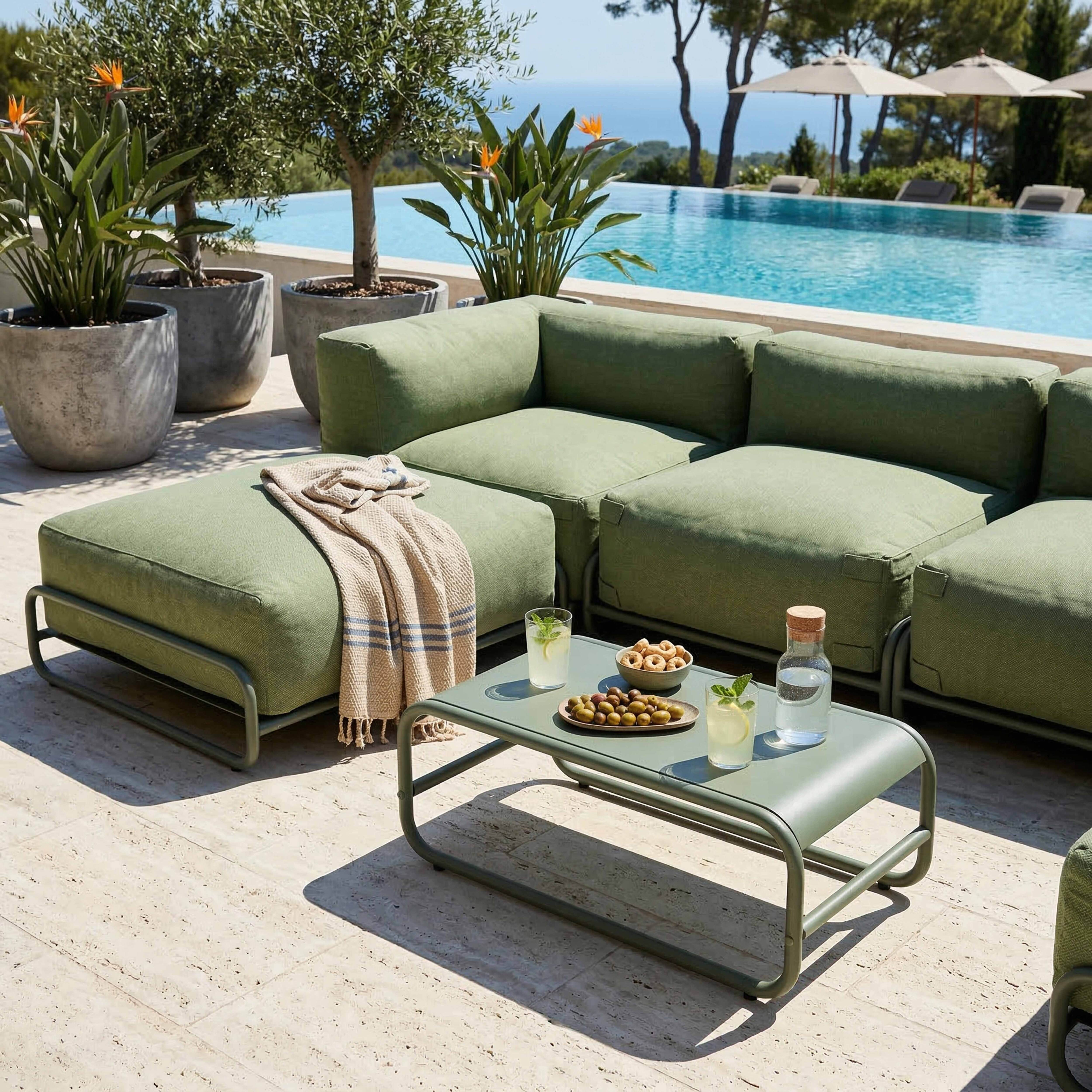 Grüne Lounge-Möbel am Pool mit Getränken und Snacks. Oliven, Kekse, Wasserflasche.