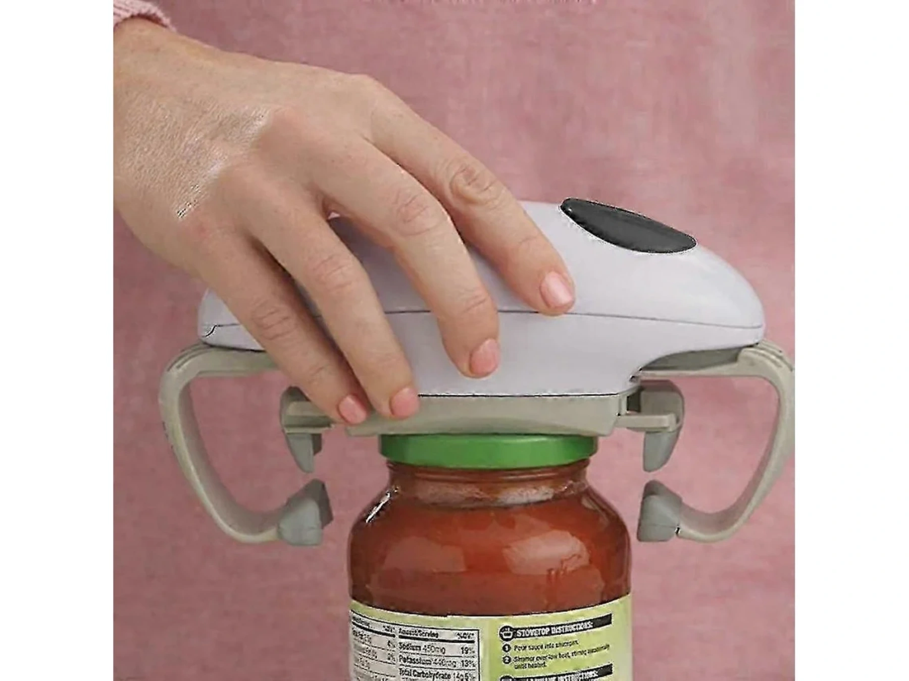 Eine Hand hält einen automatischen Dosenöffner, der auf einem Glas mit roter Soße sitzt.