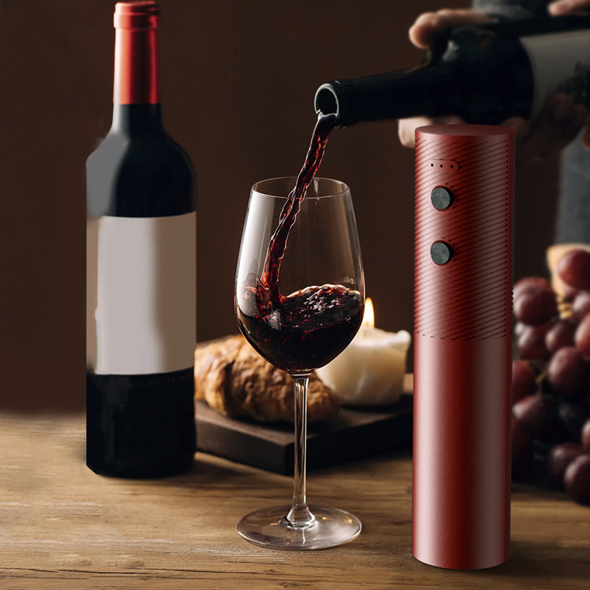 Rotwein wird in ein Glas gegossen, daneben eine Flasche, Kerze, Croissant und Trauben.