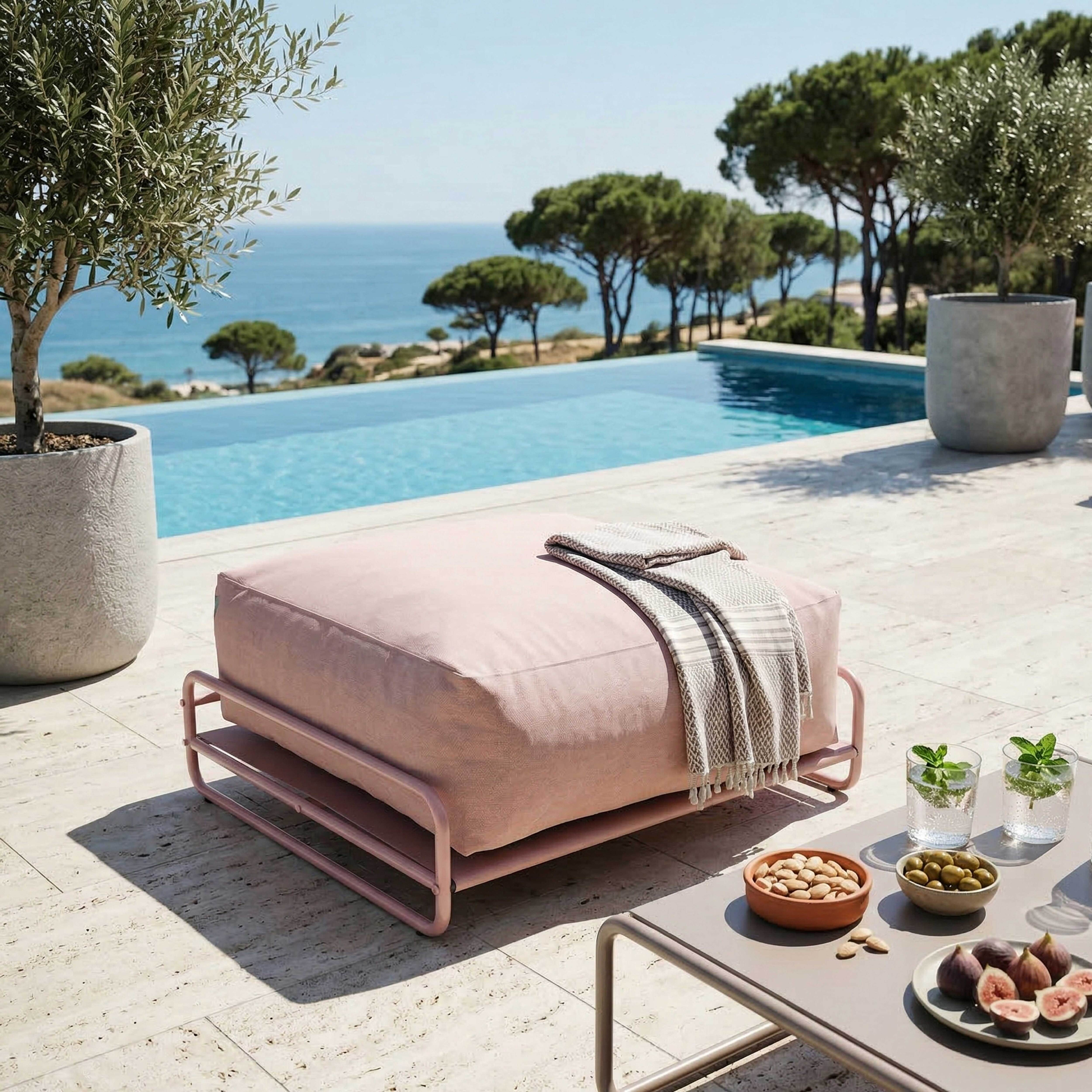 Ein rosa Sitzsack neben einem Pool mit Meerblick.