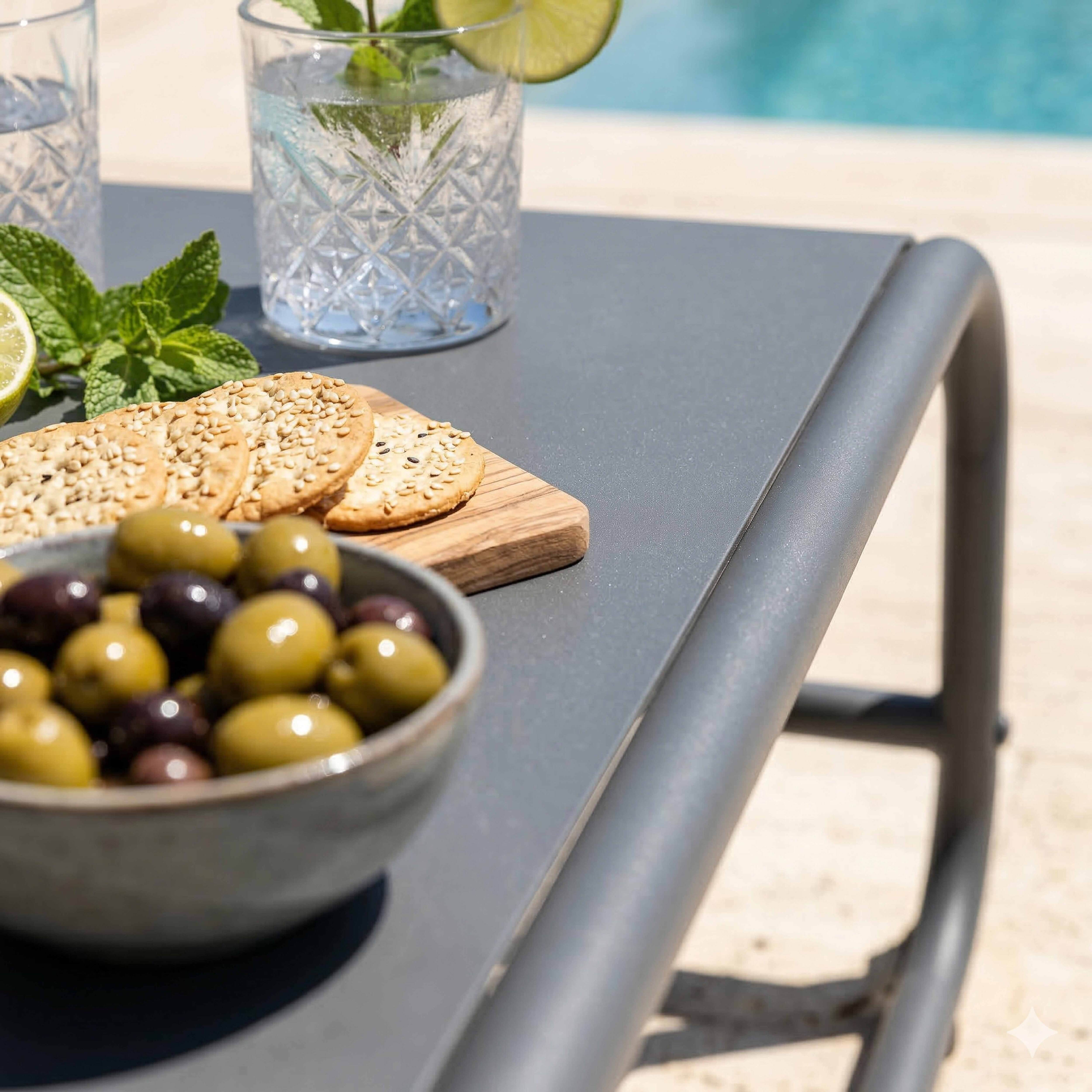 Eine Schüssel Oliven, Kekse und Getränke auf einem Tisch am Pool.