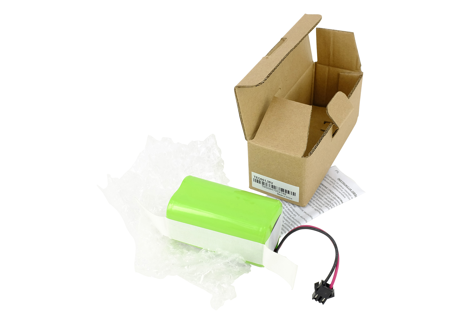 Eine grüne Batterie mit Kabeln liegt neben einer geöffneten Pappschachtel.