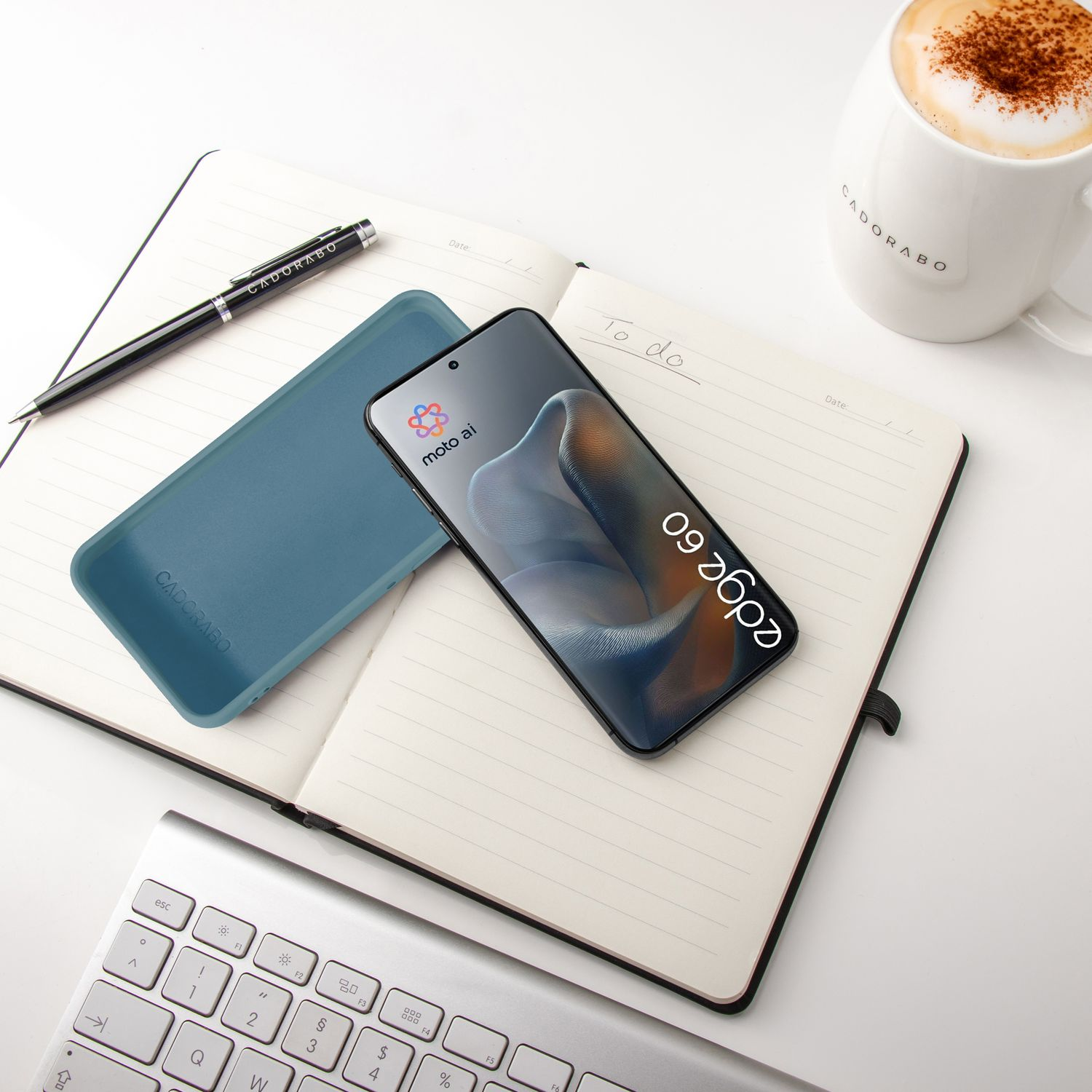 Ein Smartphone, eine Hülle, ein Notizbuch und eine Kaffeetasse auf einem Schreibtisch.