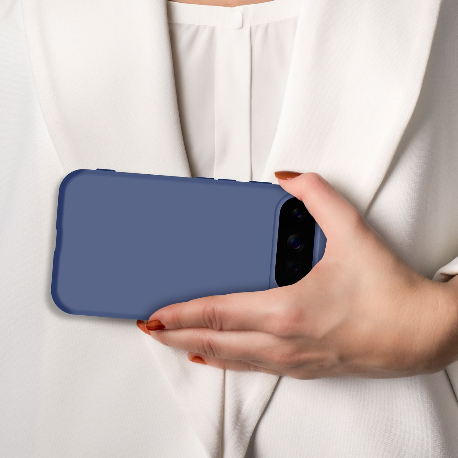 Eine Hand hält ein blaues Smartphone vor einem weißen Hemd.